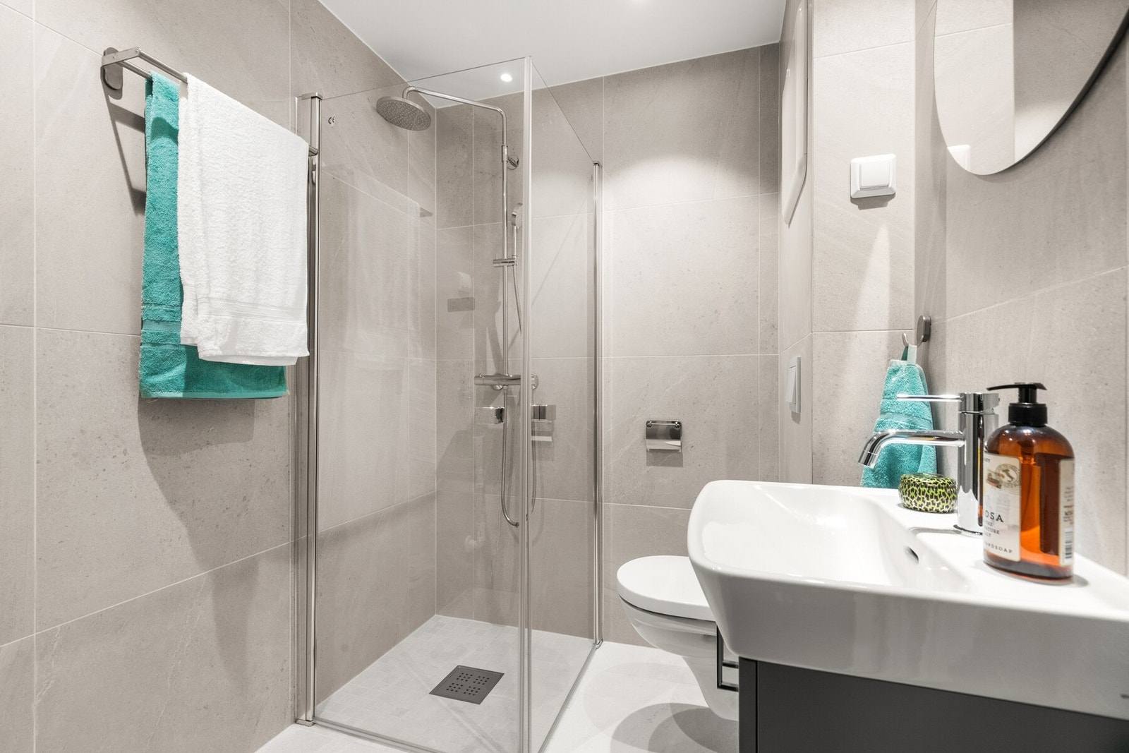 Lekkert baderom fra 2019 med servant, vegghengt wc, dusj med glassdører og opplegg for vaskemaskin. Galleribilde