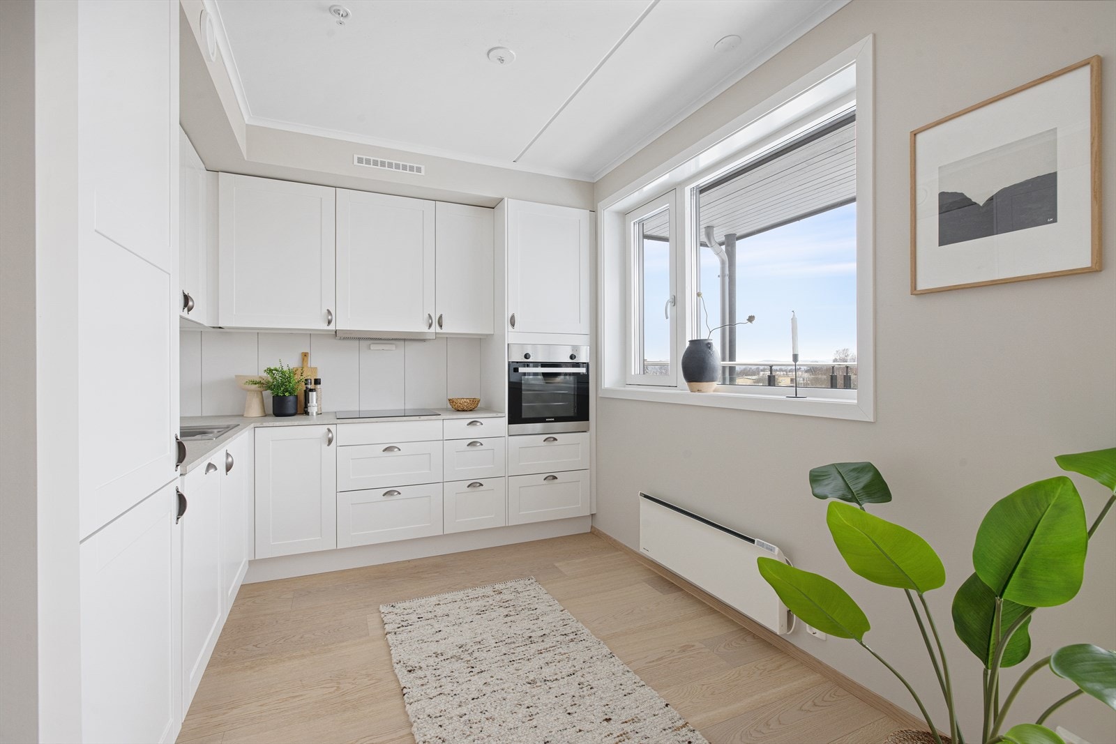 Pen kjøkkeninnredning med hvite lett profilerte fronter på over- og underskap, fra Sigdal Scala Galleribilde