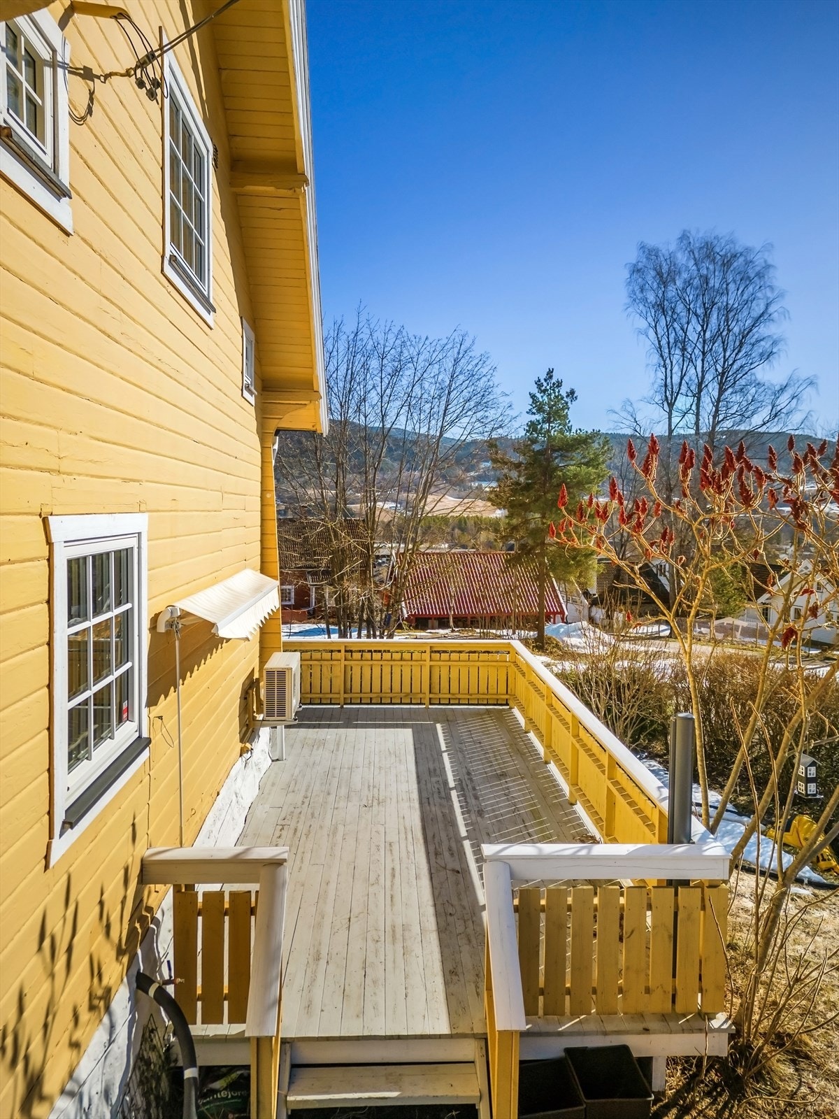 Videre er det trappeadkomst til en større terrasse som strekker seg rundt to sider av boligen Galleribilde