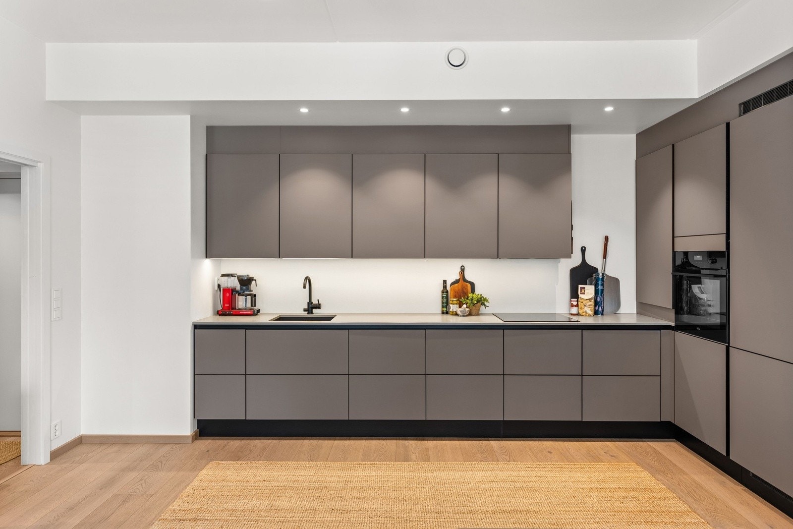 Stilrent kjøkken fra HTH m/integrerte hvitevarer og benkeplate i kompositt. Galleribilde