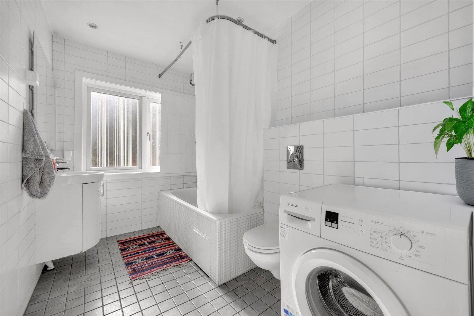 Flislagt bad med gulvvarme fra 2006. Himling med malte plater og innfelt downlights. Opplegg for vaskemaskin. Galleribilde