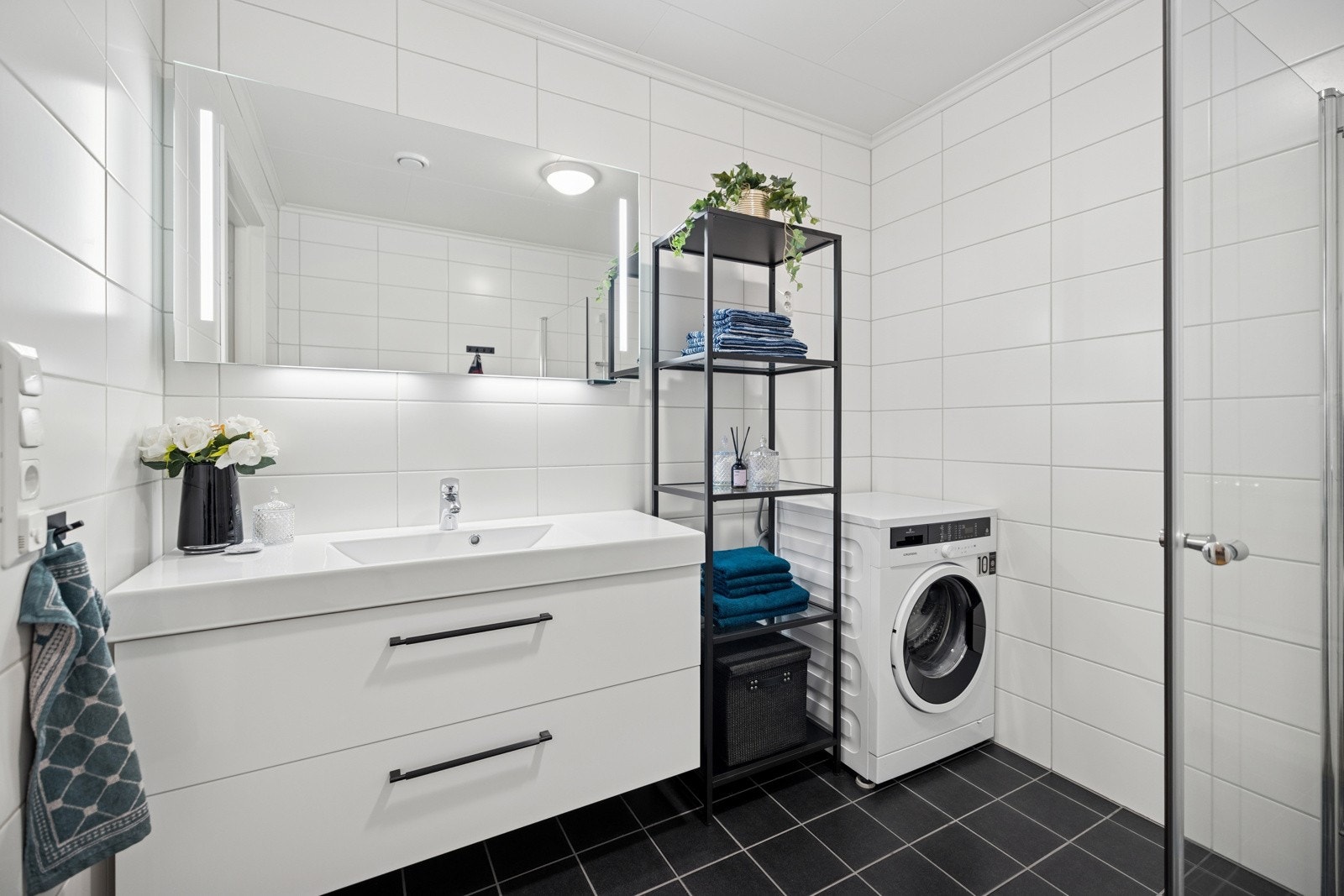 Det pene baderommet har moderne fremtoning med heldekkende servant over underskap med speil som har belysningesfelt over Galleribilde