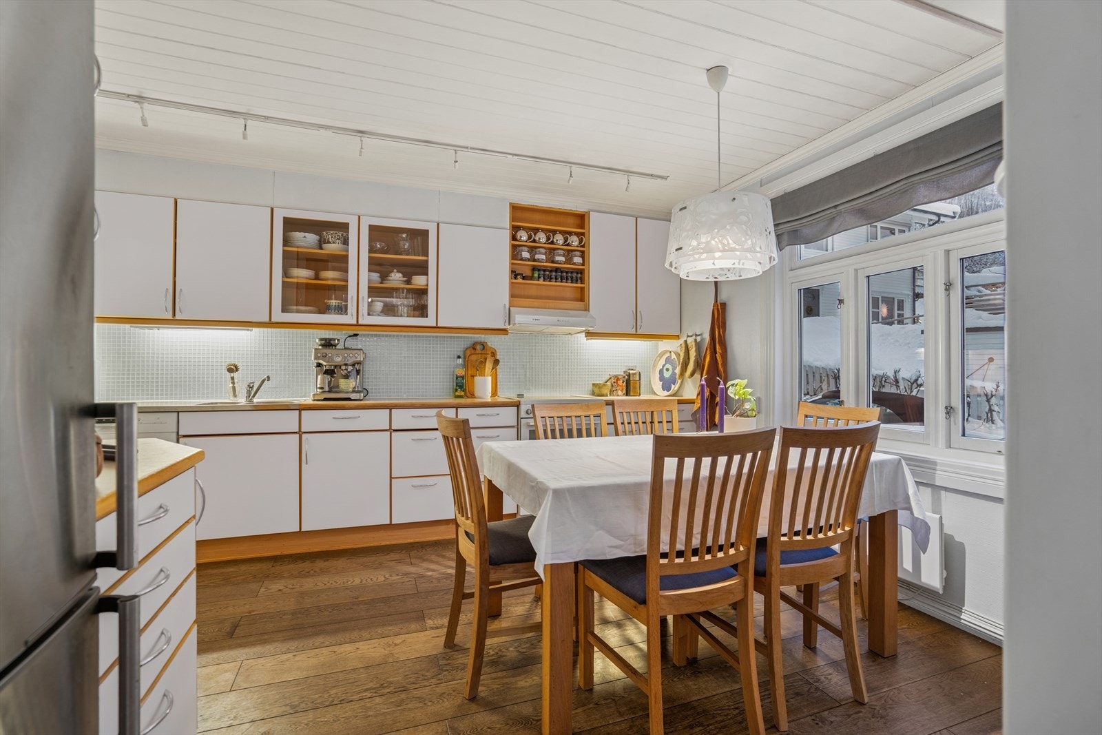 Kjøkkeninnredningen er lys med laminerte skrog og slette fronter, samt flislagt vegg over benk. Galleribilde