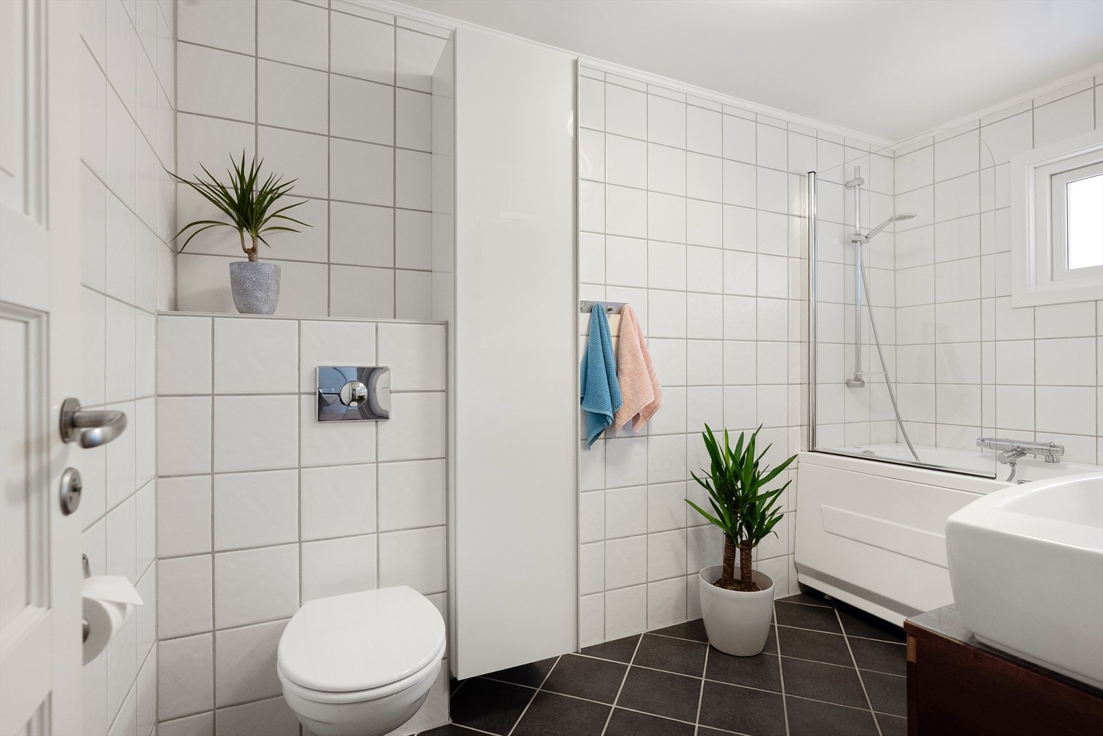 Badet har vegghengt toalett og dusjløsning i badekar. Galleribilde