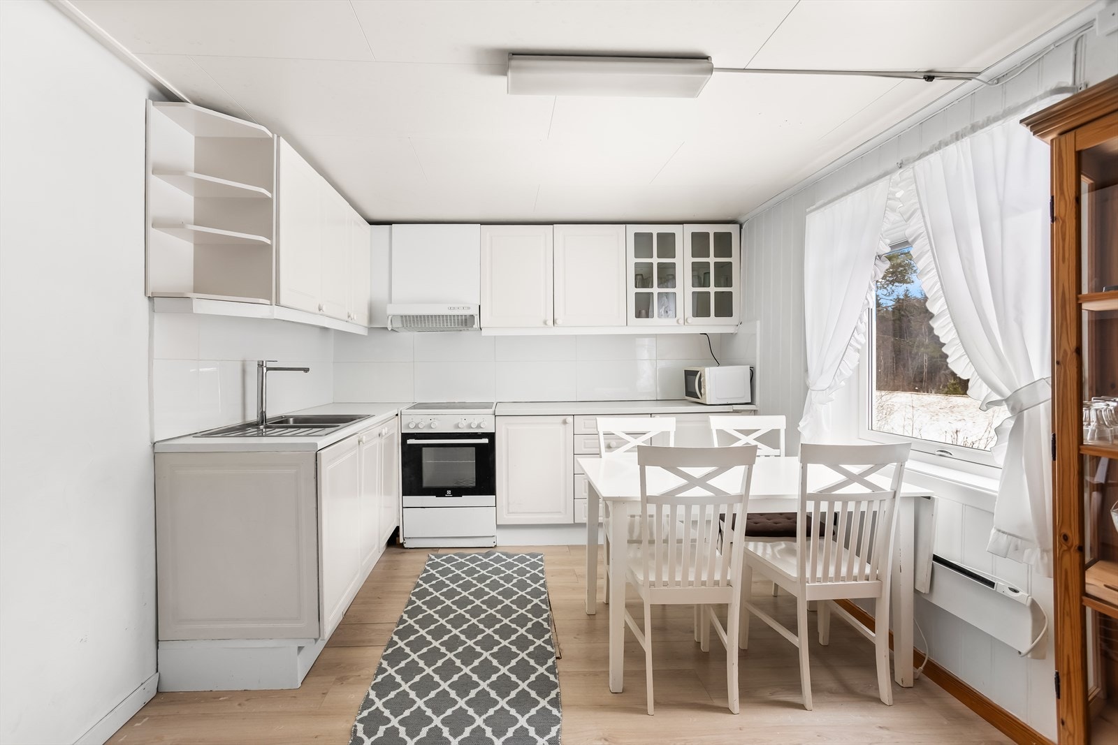 Kjøkkeninnredningen har hvite, glatte fronter og fliser over benken. Galleribilde