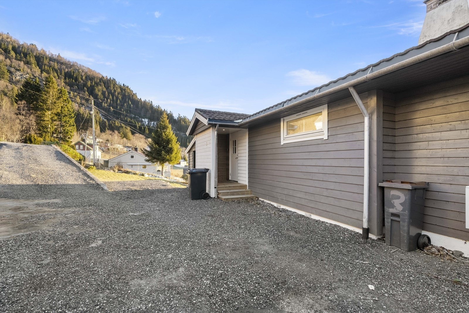 Ved inngangspartiet er det opparbeida gruslagt tunplass med parkering for fleire bilar Galleribilde