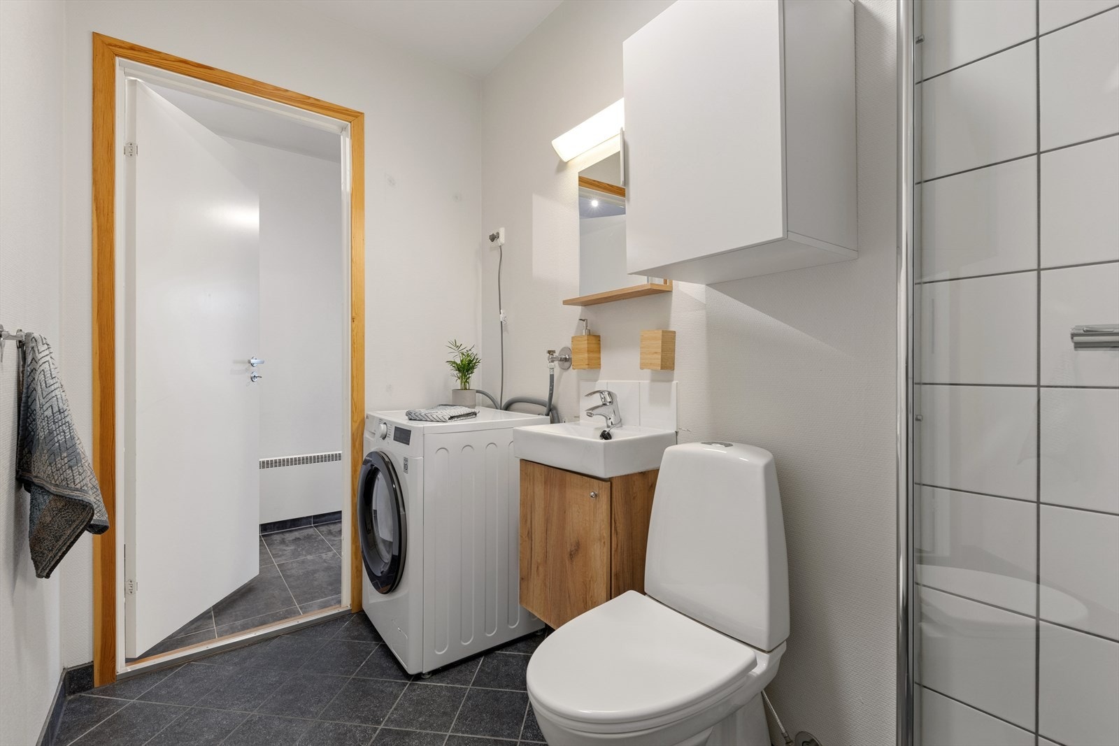 Badet er ellers utstyrt med dusjhjørne, toalett og baderomsinnredning med servant. I tillegg har man opplegg for vaskemaskin. Galleribilde