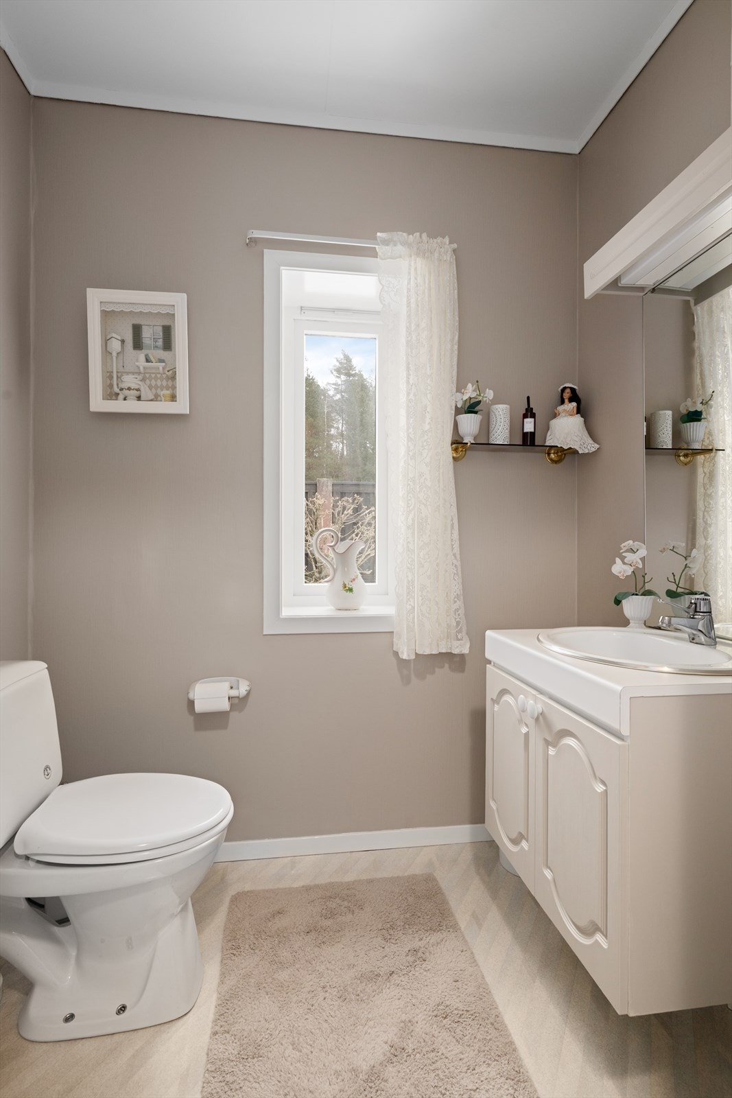 Boligen har toalettrom ved gangen i 1. etasje, med duse fargetoner og innredning med nedfelt servant. Toalettrommet har belegg på gulvet og malte veggoverflater. Panelovn for oppvarming. Galleribilde