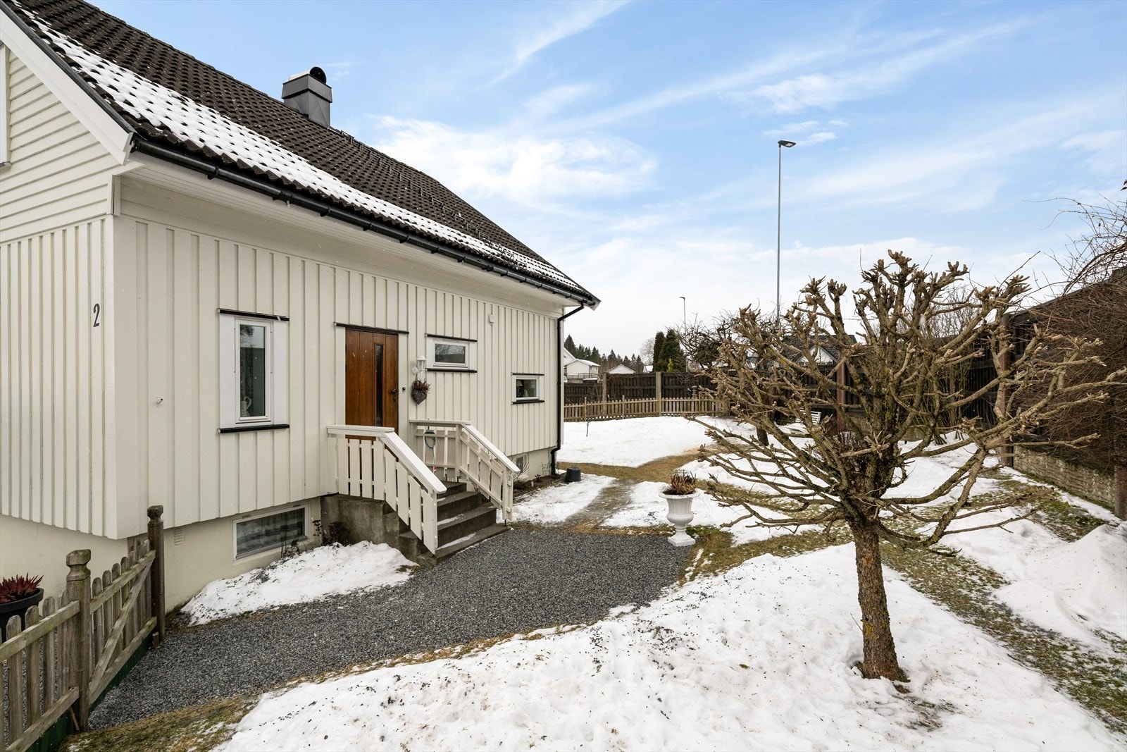 Fra carporten er det gruset gangsti opp til boligens inngangsparti og den veletablerte hagen som er fint inngjerdet på alle kanter. Galleribilde