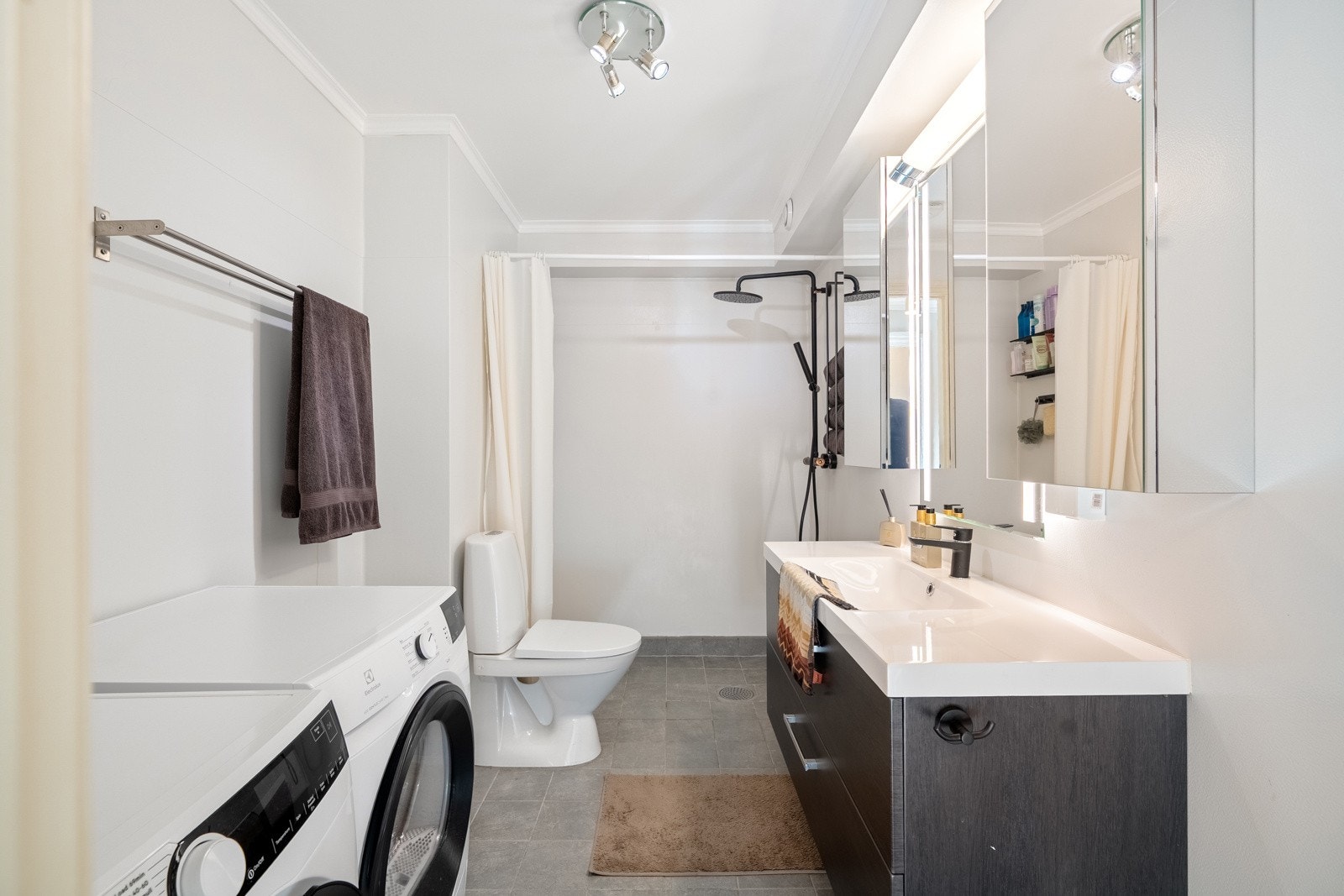 Badet i leiligheten er innredet med seksjon med helservant, speilskap med belysning, gulvstående toalett og dusjhjørne. Galleribilde