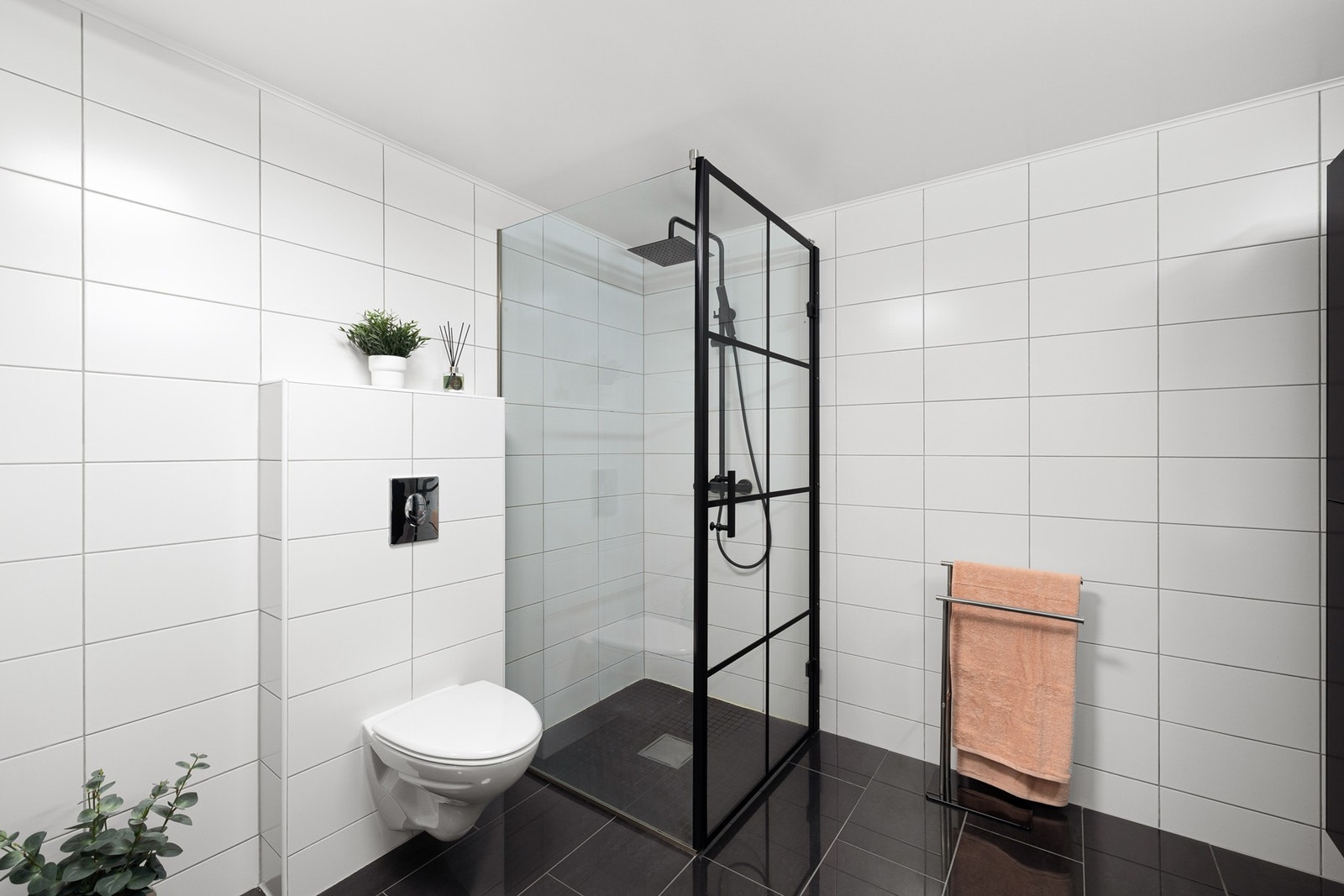 Dusjhjørne med sorte detaljer og deilig regnfallsdusj. Det er opplegg for vaskemaskin. Galleribilde