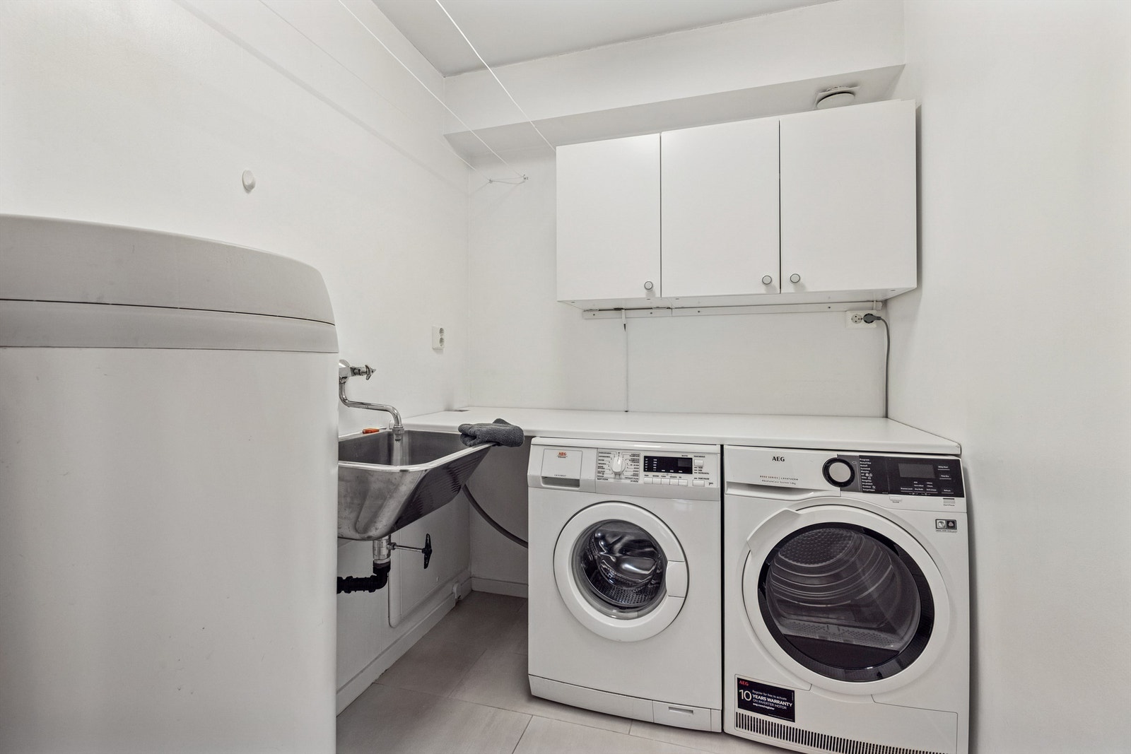 Praktisk vaskerom med skyllekum og opplegg for vaskemaskin og tørketrommel. Galleribilde