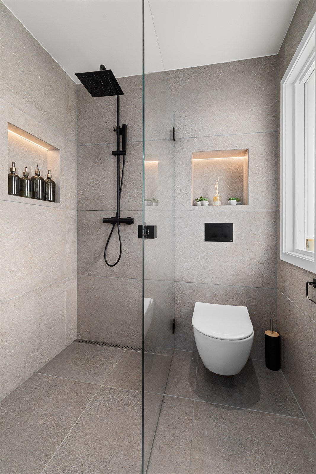 Innredet med dusjnisje med glassvegg, samt vegghengt toalett Galleribilde