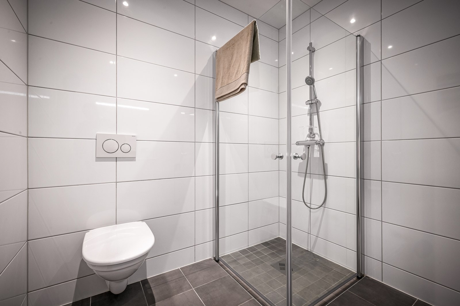 Baderommet er innredet med vegghengt toalett, dusjvegger og servant med underskap. Galleribilde