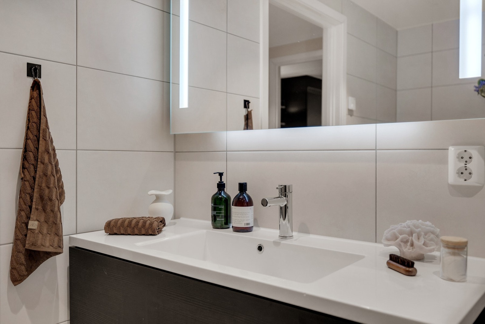 Innredningen består av benkeskap med glatte fronter, servant, veggfestet toalett og dusj med innfellbare glassdører i herdet glass. Galleribilde