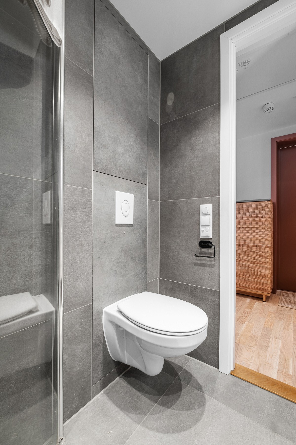 Badet innehar dusjvegger av glass med dusjgarnityr på vegg, vegghengt toalett, innredning med servant og røropplegg for vaskemaskin. Galleribilde