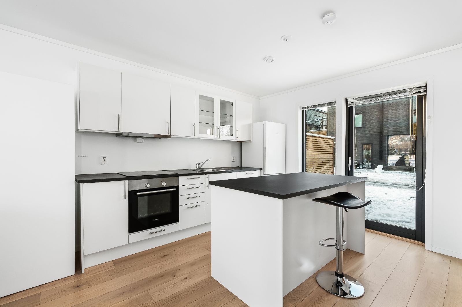 Moderne kjøkken med hvite slette flater og integrert stekeovn, steketopp og oppvaskmaskin.Barløsning Galleribilde