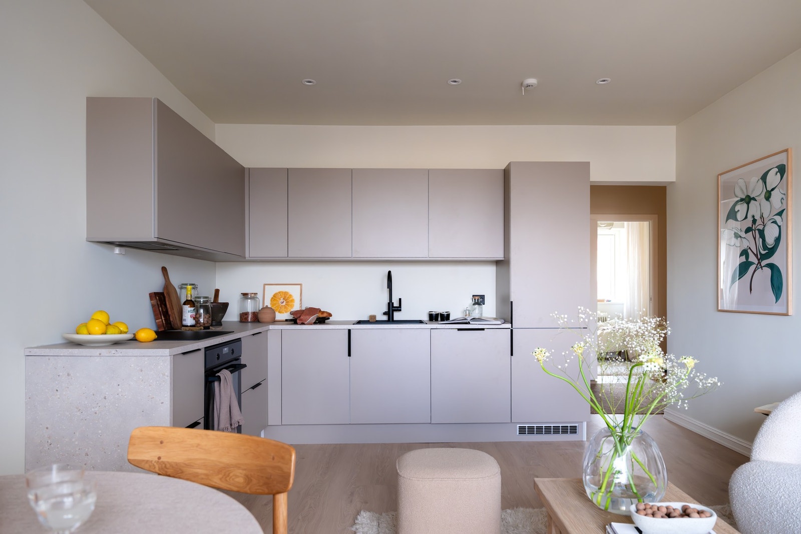 Kjøkkenet er holdt i en moderne beigefarge med glatte fronter og en stilren benkeplate i laminat, samt oppvaskkum i kompositt. Galleribilde