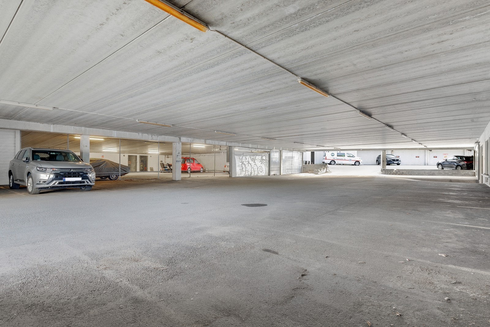 Man har utvendig parkeringsplass ( fritt) enten under tak eller utenfor bygget. I tillegg 2 boder som man kan se til venstre i bilde med gitterdører. Galleribilde