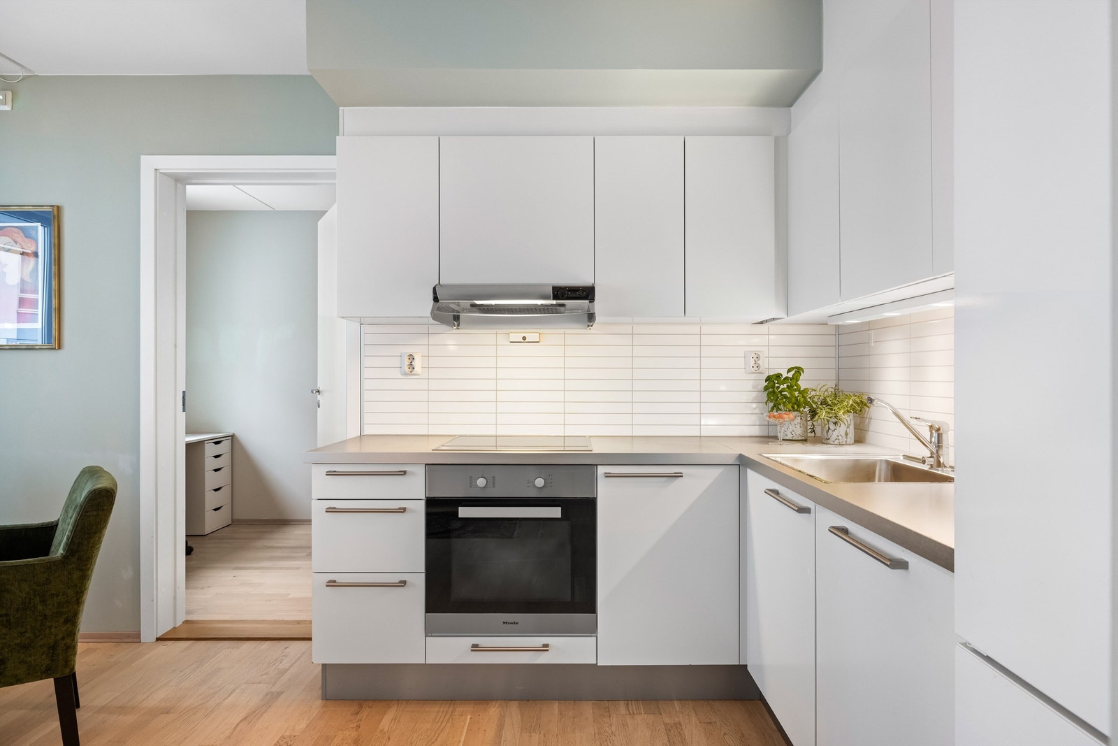 Kjøkkenet har en lekker hjørneløsning med glatte, hvite fronter og god benkeplass. Galleribilde