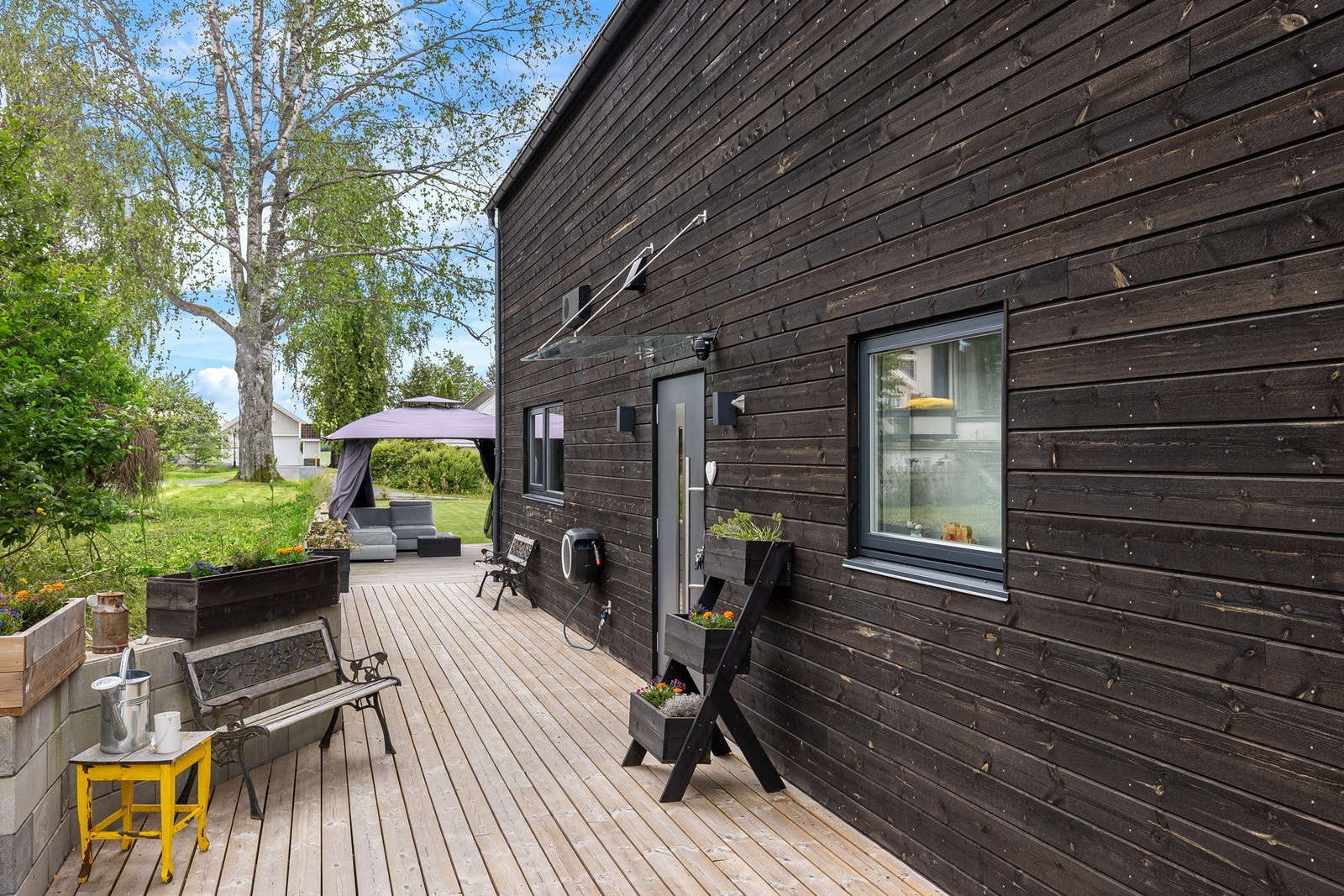 Stor terrasseplatting som strekker seg rundt boligen 3 sider. Glassplate over inngangspartiet Galleribilde