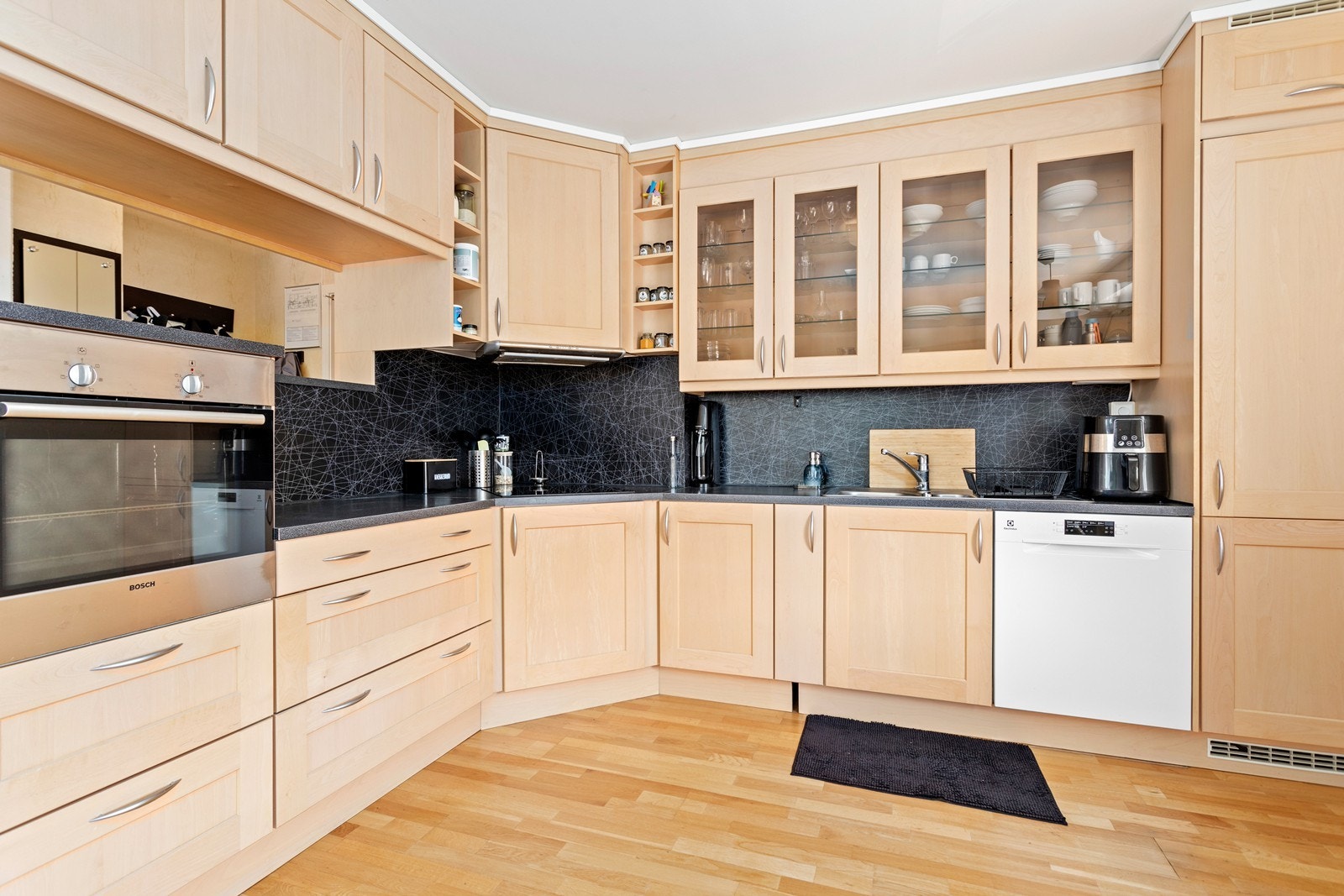 Kjøkkeninnreiinga har lyse profilerte frontar og benkeplate i laminat med platetopp, steikeomn og kjøl/fryseskap integrert i innredningen. Frittståande oppvaskmaskin. Galleribilde