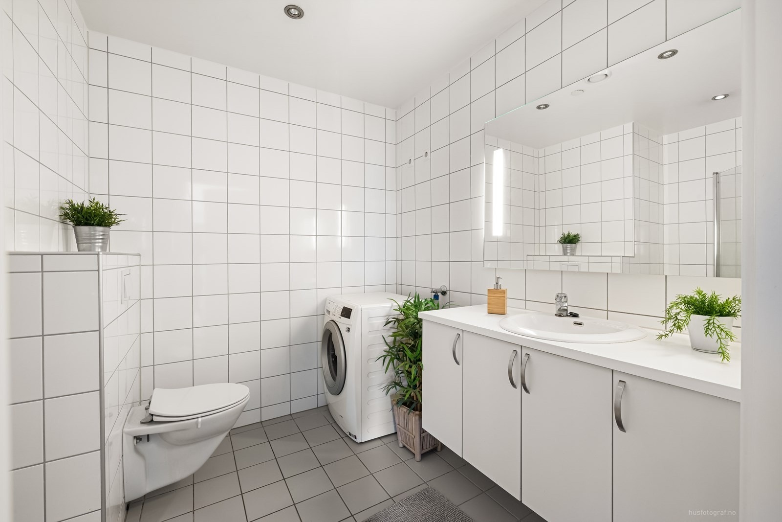 Lyst, flislagt bad med varmekabler i gulv. Servant i innredningen. Vegghengt wc. Opplegg til vaskemaskin. Galleribilde