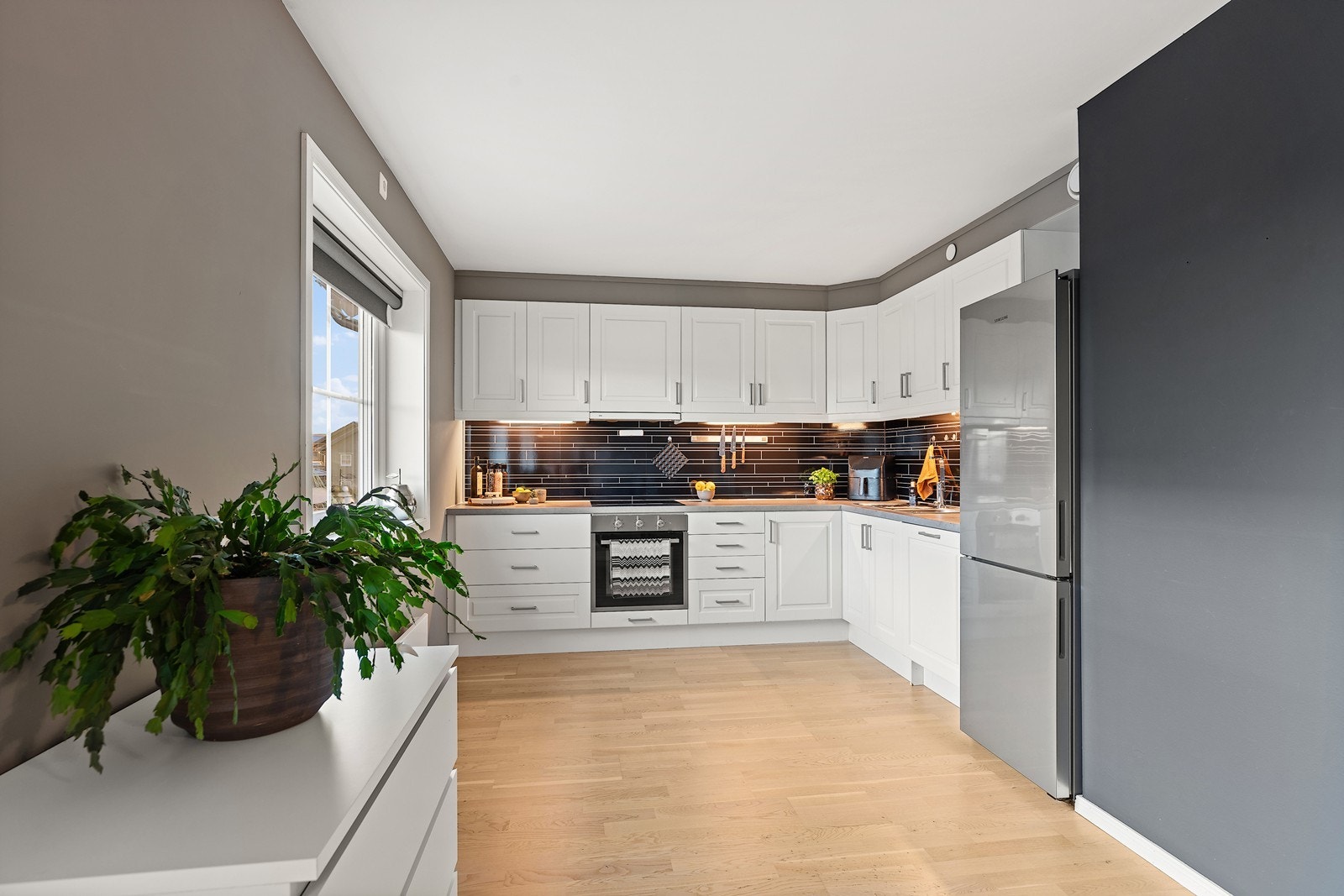 Kjøkkenet i leiligheten har en klassisk og tidløs innredning med hvite profilerte fronter og en laminert benkeplate. Galleribilde