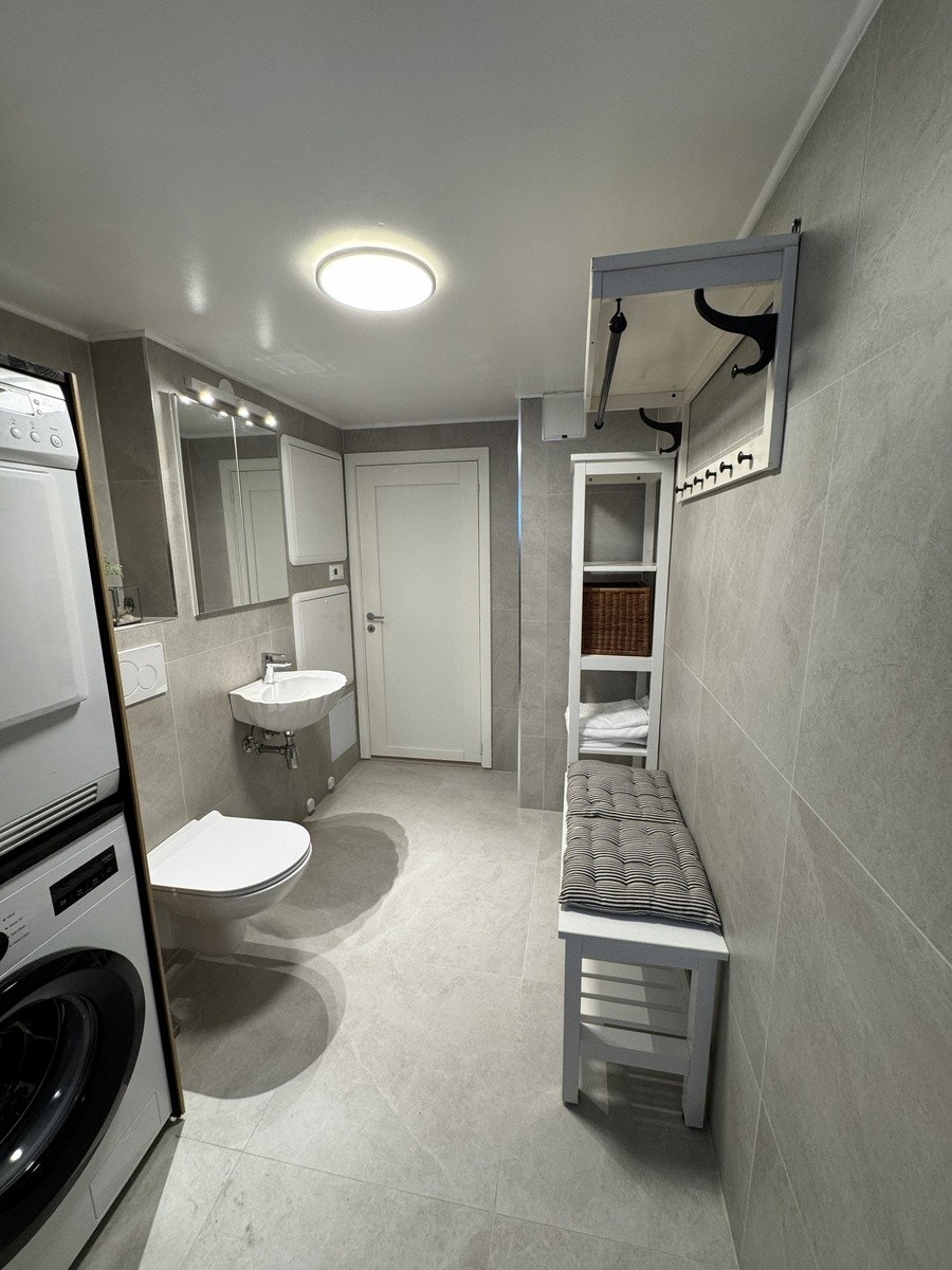 Bad med veggmontert toalett, vaskemaskin og tørketrommel Galleribilde