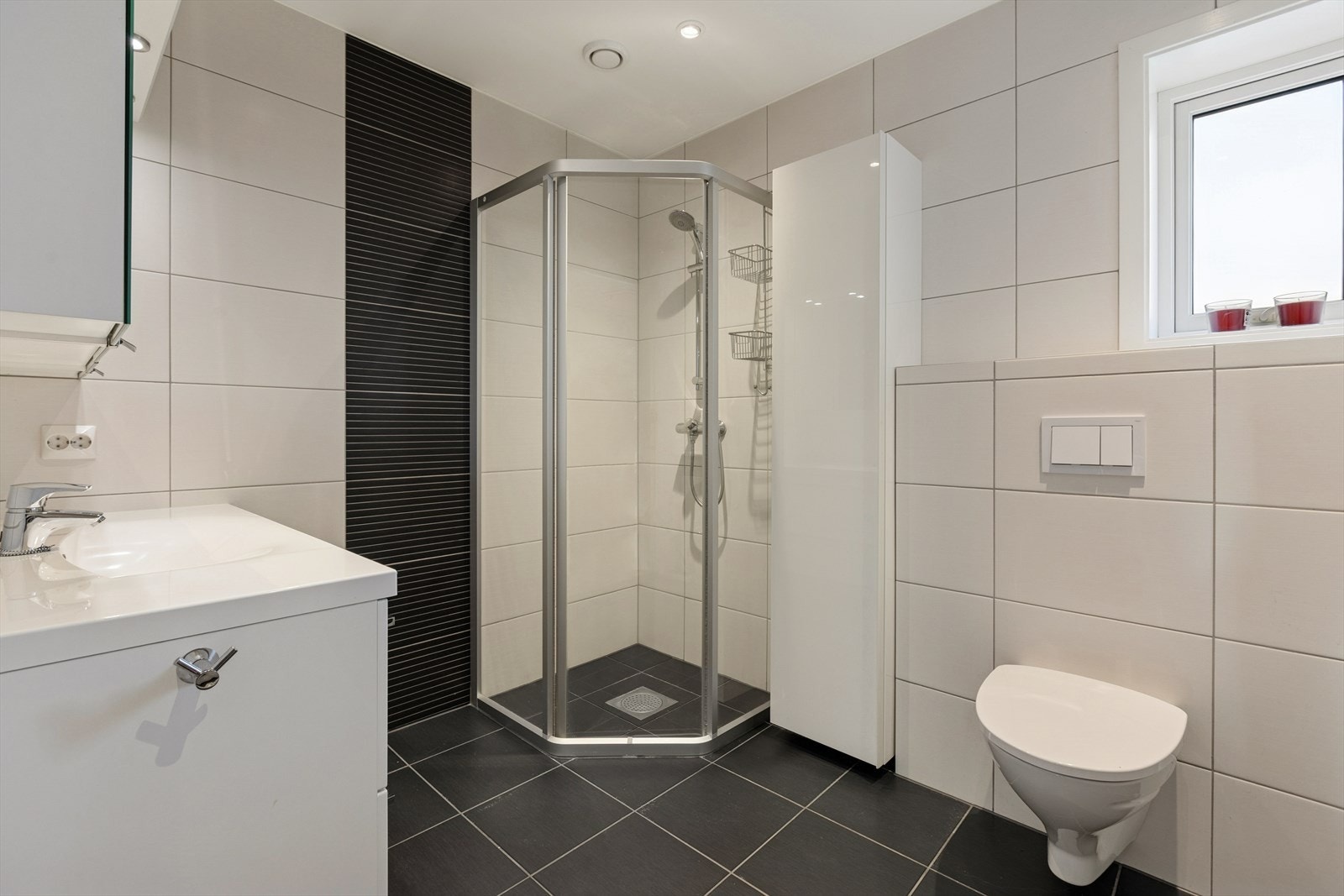 Baderommet i andre etasje er innredet i tilsvarende stil som badet i første etasje med en kombinasjon av lyse og mørke fliser på gulv og vegger. Galleribilde