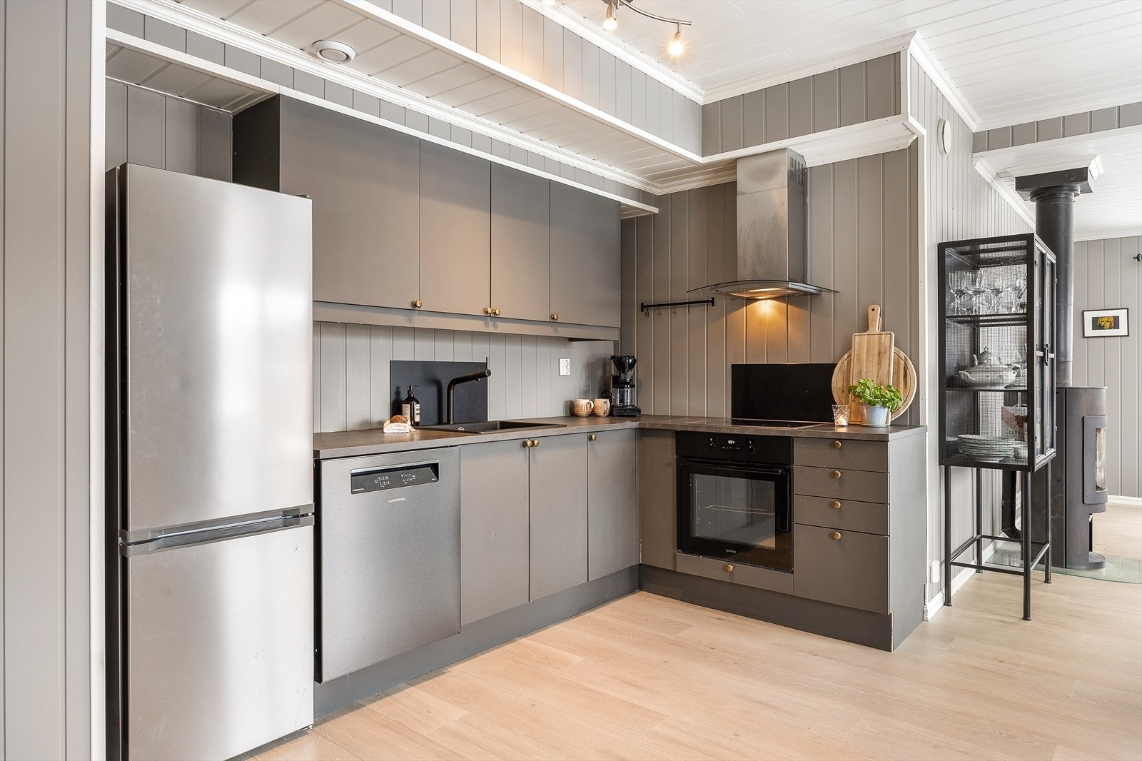 Innredningen har grå, glatte fronter og laminatbenkeplate med sort oppvaskkum i kompositt. Galleribilde