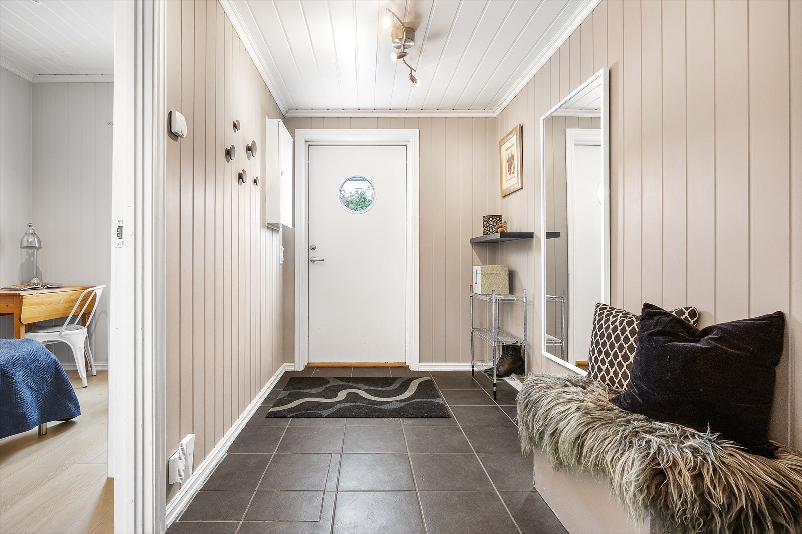 Vel inne har entréen sorte gulvfliser og lysmalte panelplater. Galleribilde