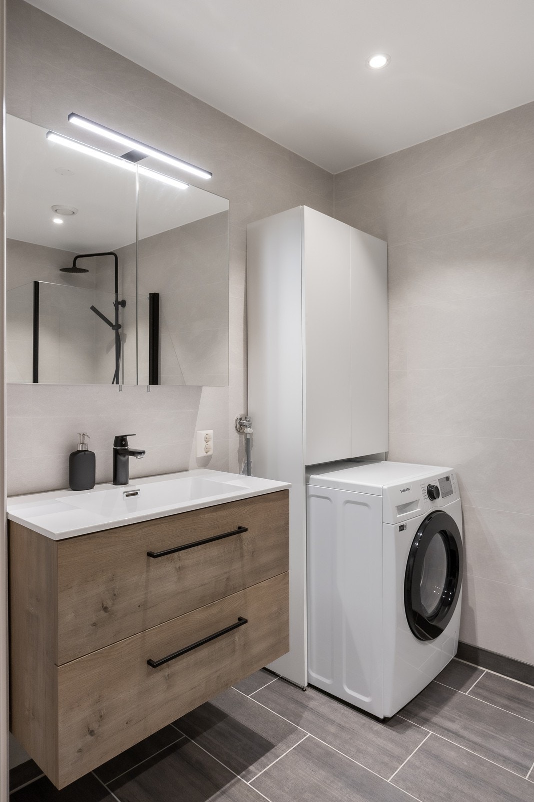 Innredningen består av servant over skuffeseksjon og et tilhørende speilskap med belysning. Ved siden av er et hvitt høyskap med nisje for vaskemaskin. Galleribilde