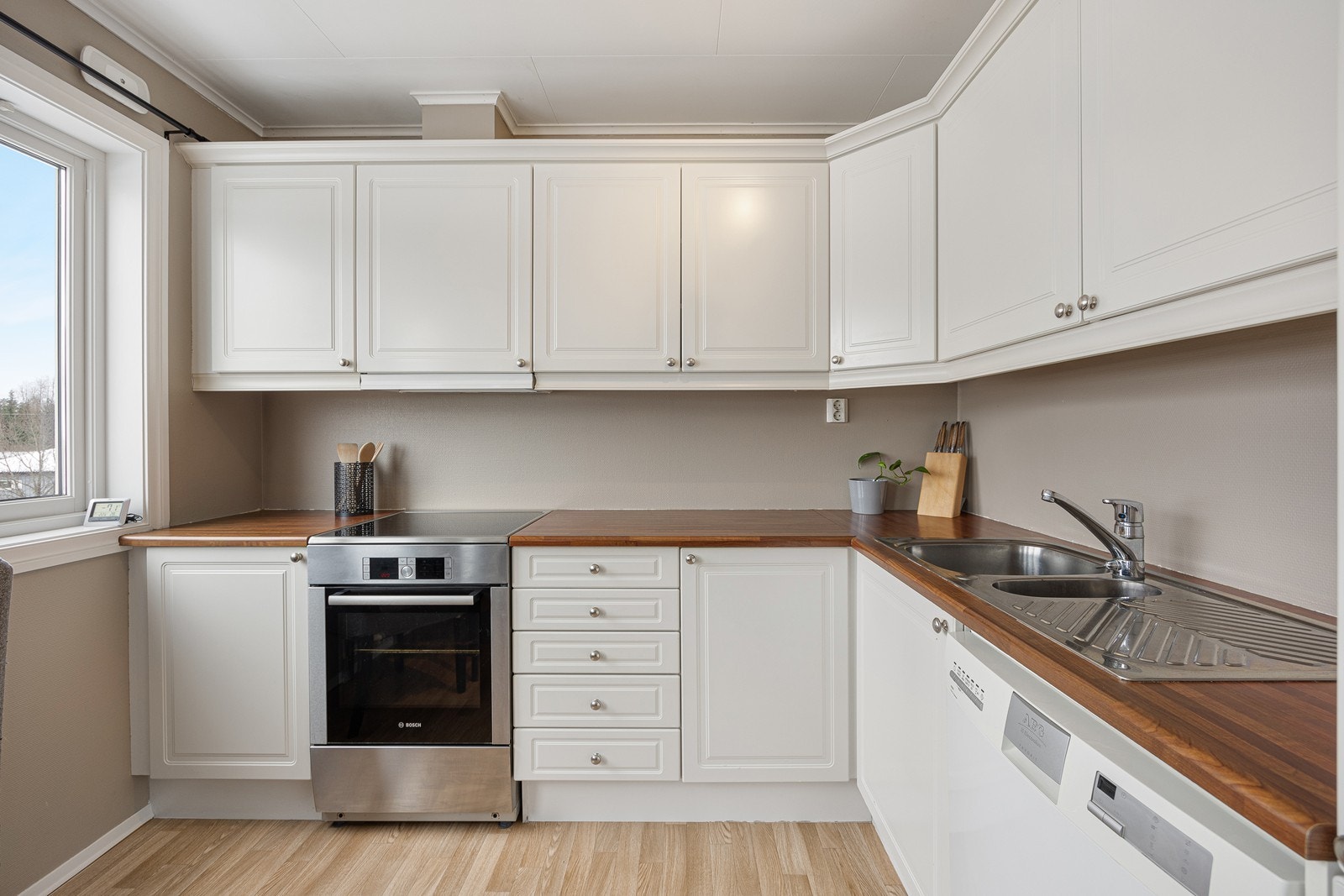 Innredningen har hvite, profilerte fronter og laminatbenkeplate med dobbel oppvaskkum. Galleribilde