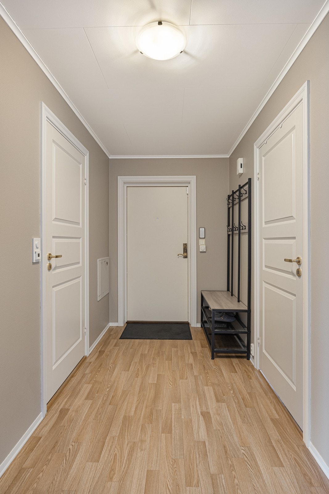 Entréen har en lys, behagelig fargepalett med gyllent gulvbelegg og vegger i en varm nyanse. Galleribilde