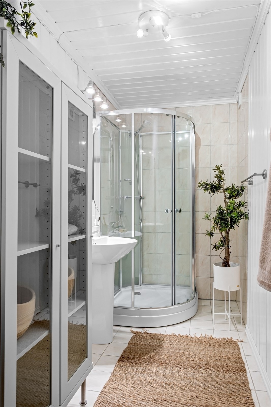 Badet har flislagt gulv, varmekabler og er av ukjent alder. Her er søylevask, stort oppbevaringsskap og dusjkabinett. Galleribilde