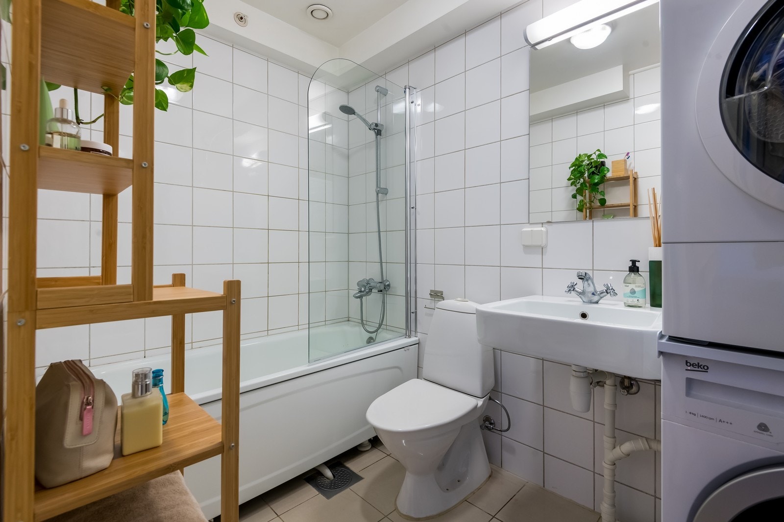 Flislagt baderom med badekar, dusj og opplegg for vaskemaskin. Galleribilde