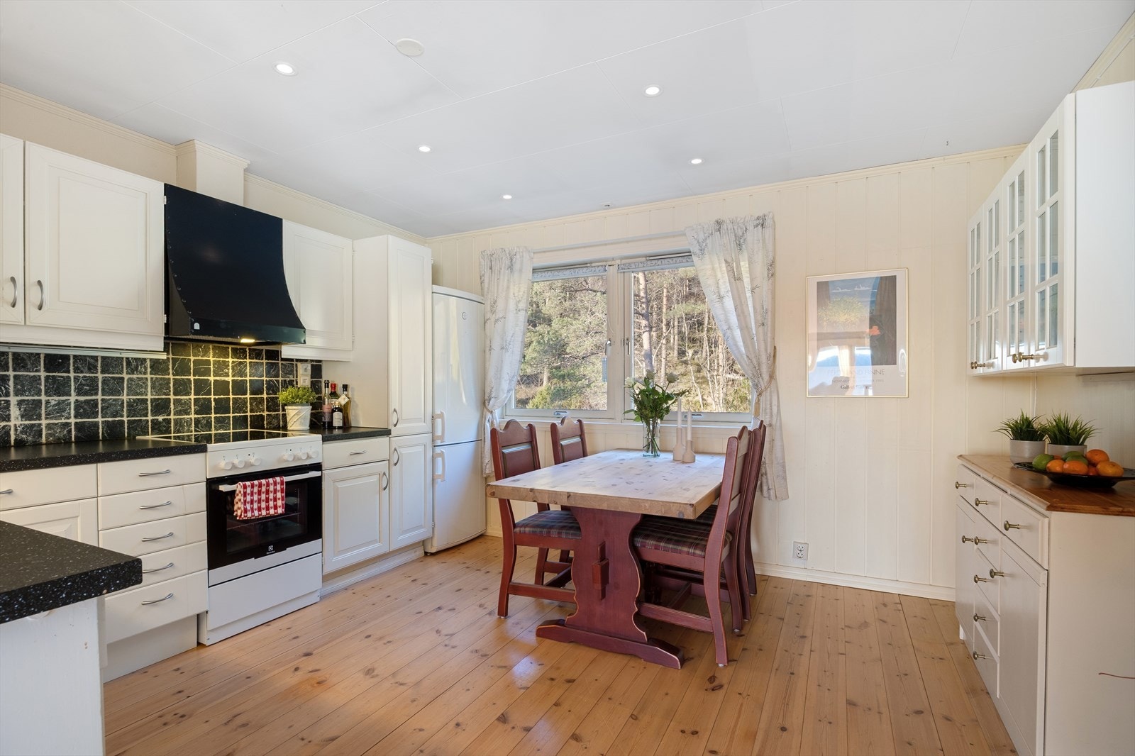 Kjøkkenet har lyse, profilerte fronter og god plass til spisebord Galleribilde