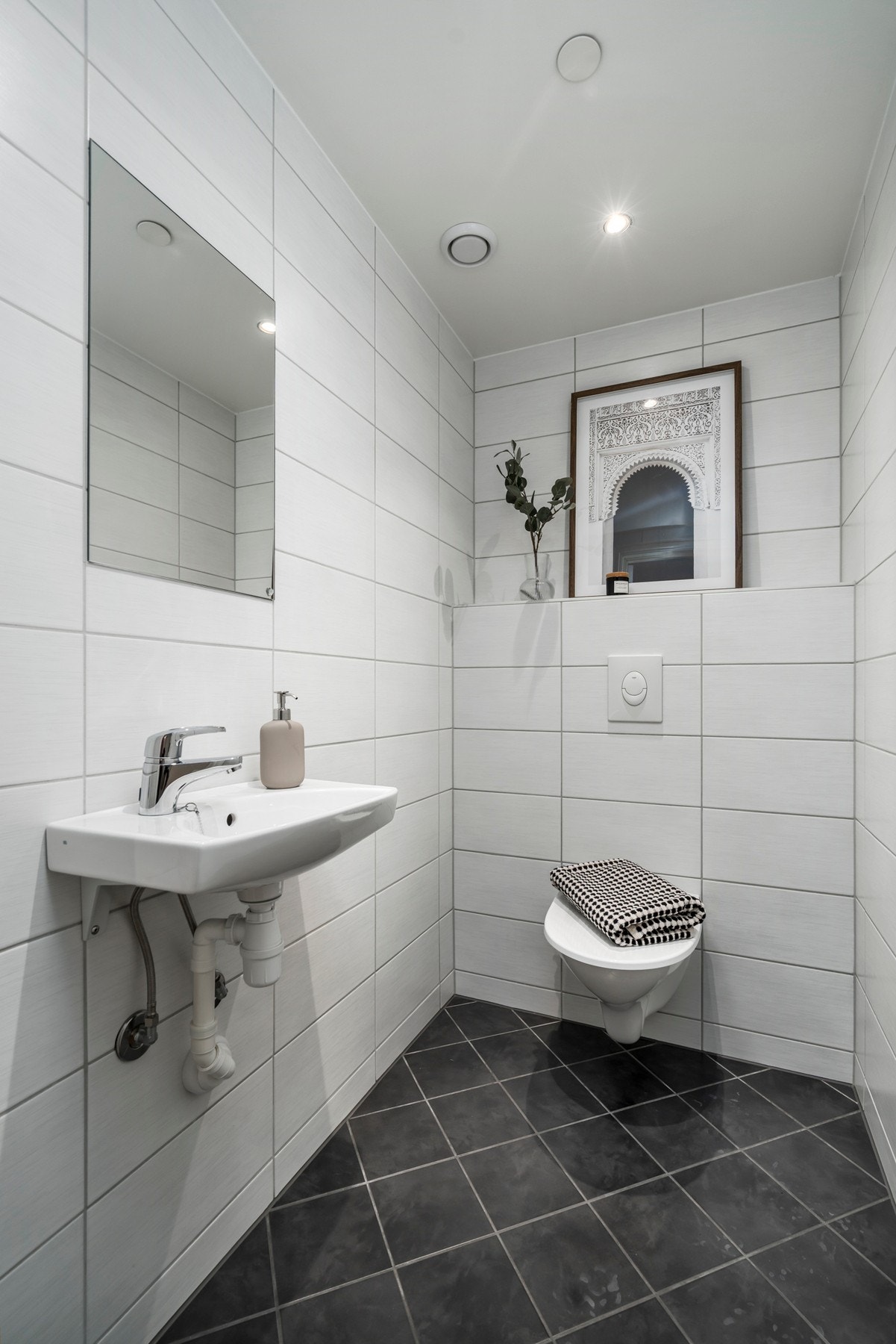 Separat toalett innredet med veggmontert toalett, enkel servant og vannbåren gulvvarme. Galleribilde