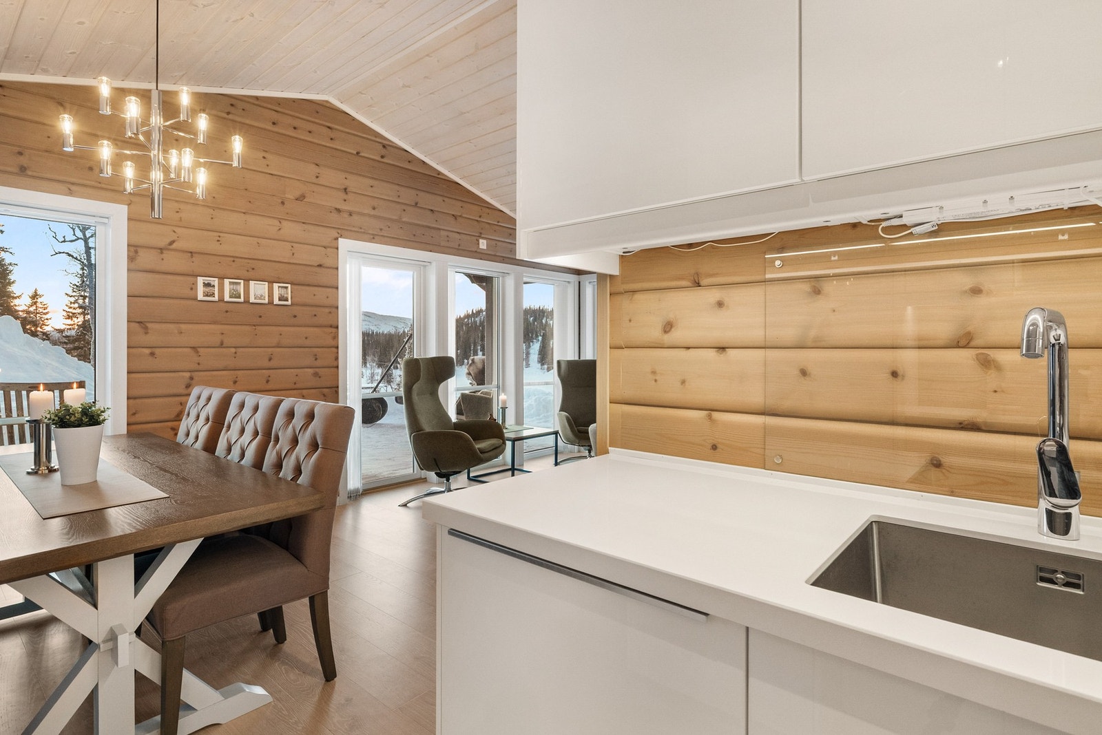 Innredet med hvite
høyglans fronter og hvit kvarts benkeplate med underlimt oppvaskkum og nedfelt induksjonstopp Galleribilde