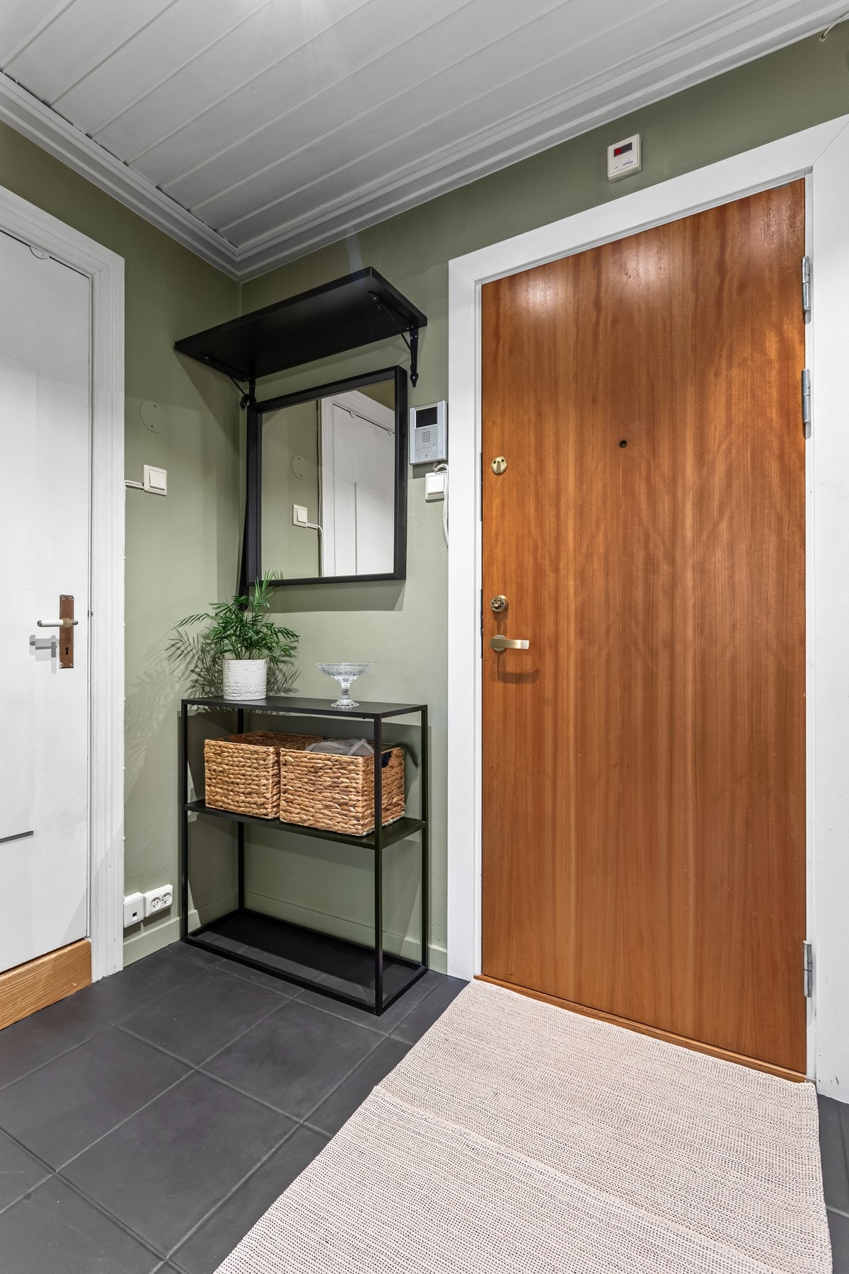 Entreen har et tidløst uttrykk med fliser på gulvet og vegger malt i en moderne tone. Galleribilde