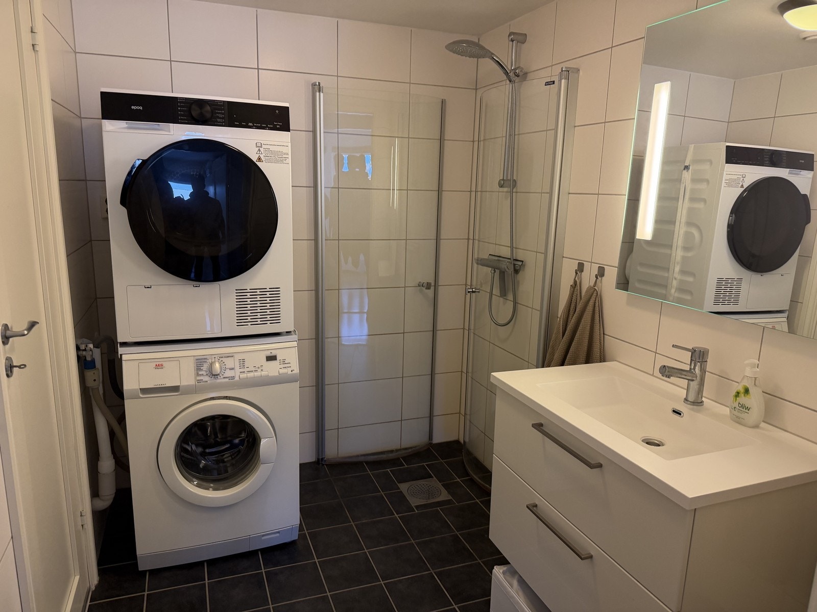 Romslig bad med innfellbare dusjdører, servant med underskap og opplegg for vaskemaskin. Galleribilde
