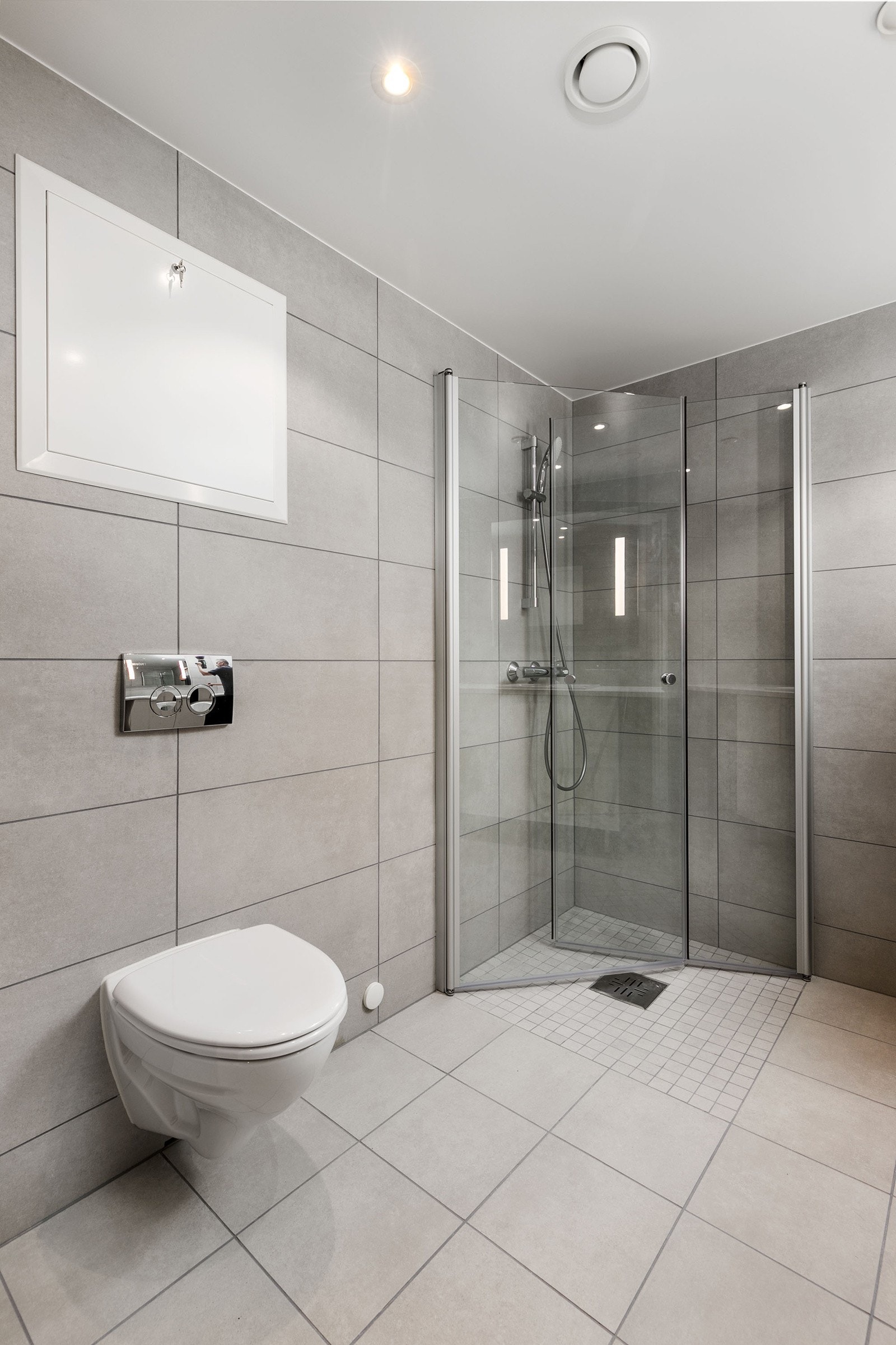 Badet har vegghengt toalett med innbygget sisterne, servant med skapinnredning samt speil med belysning. Galleribilde