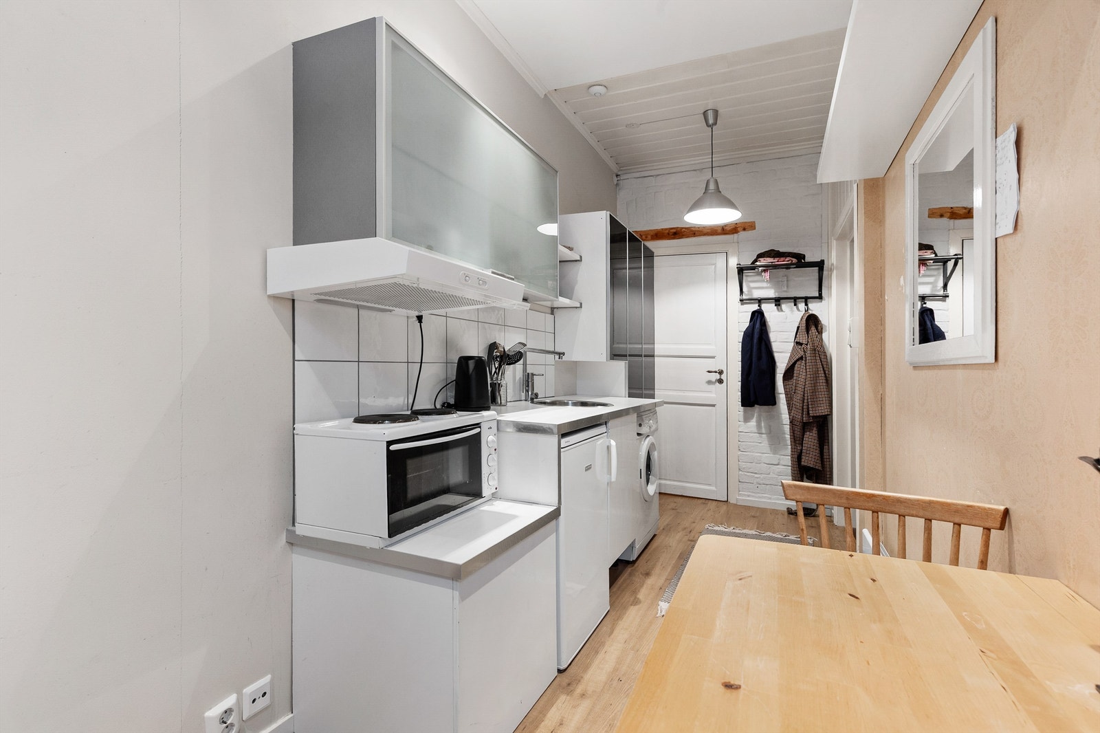 Åpen kjøkkenløsning. Innredningen er fra ukjent årstall med slette fronter. Benkeplate av laminat. Nedfelt oppvaskkum med ett-greps kjøkkenarmatur. Benkeskapsbelysning og stikkontakter over kjøkkenbenk. Frittstående kjøleskap. Ventilator i overskap. Galleribilde