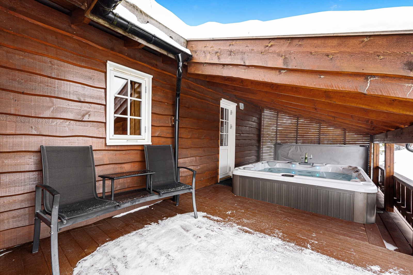 Stor terrasse mot utsikten med takoverbygg over spabadet. Galleribilde