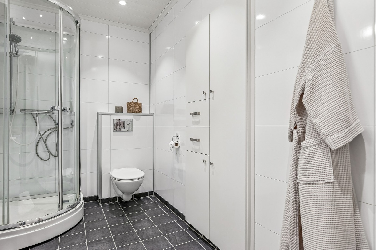 Baderommet er utstyrt med Utstyrt med dusjkabinett, mekanisk avtrekk, servant i servantskap og veggmontert wc. Galleribilde