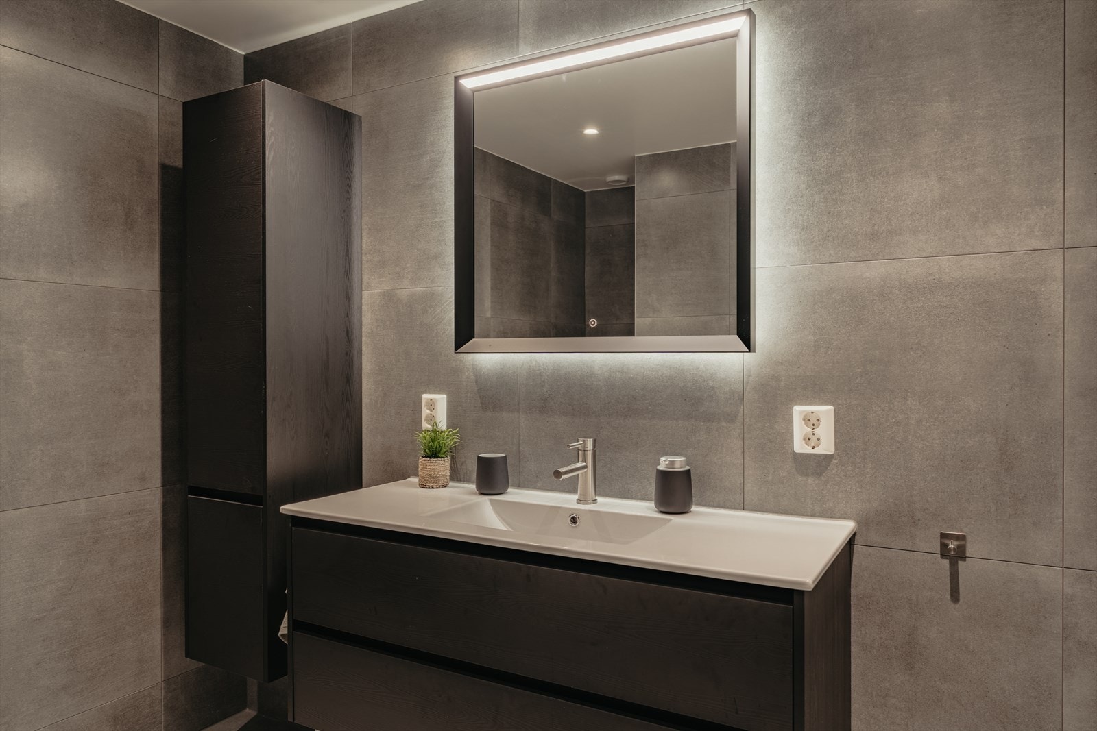 Badet er utstyrt med nedfelt servant, veggmontert toalett og dusjvegger. Galleribilde