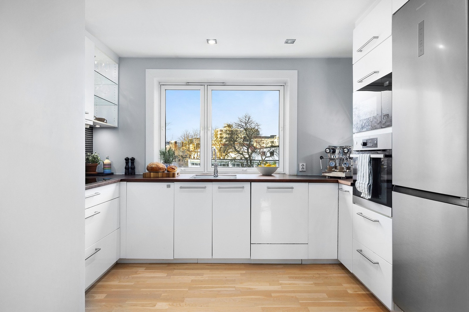 Kjøkkeninnredning med glatte fronter og benkeplate av tre med nedsenket oppvaskkum med ett-greps armatur. Galleribilde