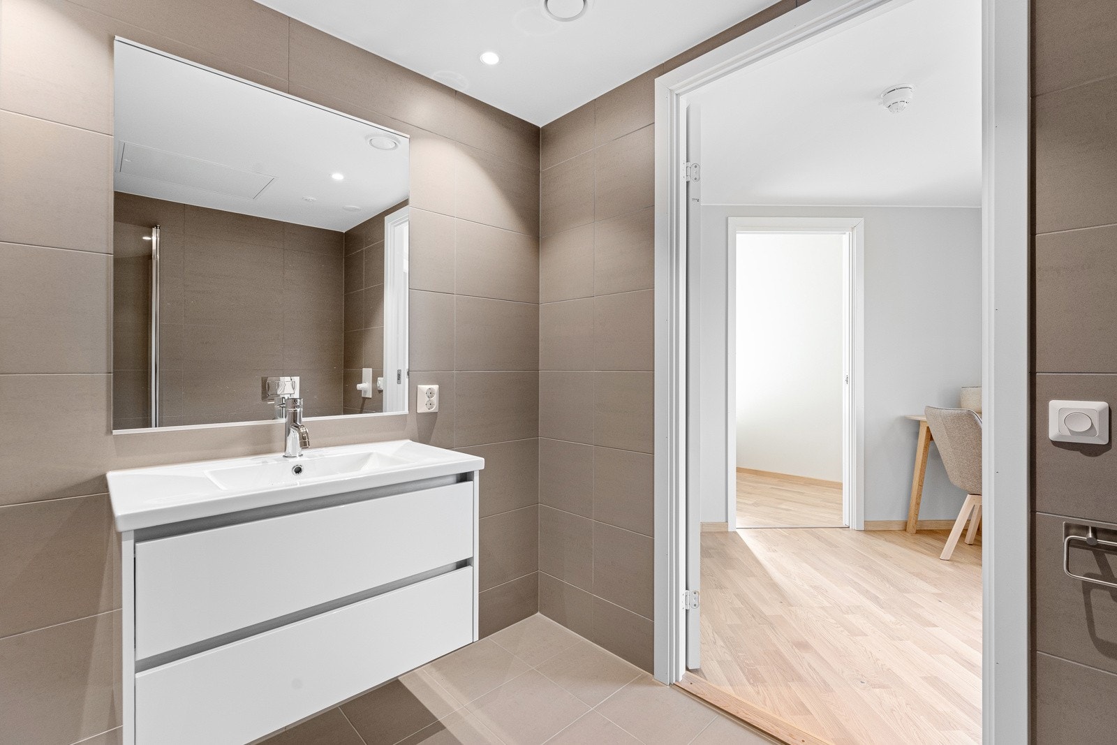 Badet er utstyrt med dusjnisje med glassdører, vegghengt toalett og servant med innredning. Opplegg for vaskemaskin og vannbåren varme i gulv. Galleribilde