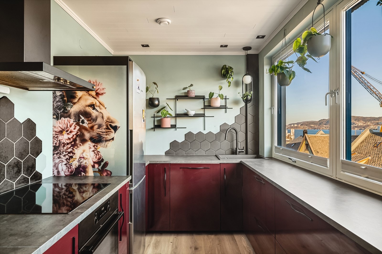 Kjøkkenet er innredet med glatte fronter, samt benkeplate av laminat og fliser på vegg ved vask og platetopp. Galleribilde